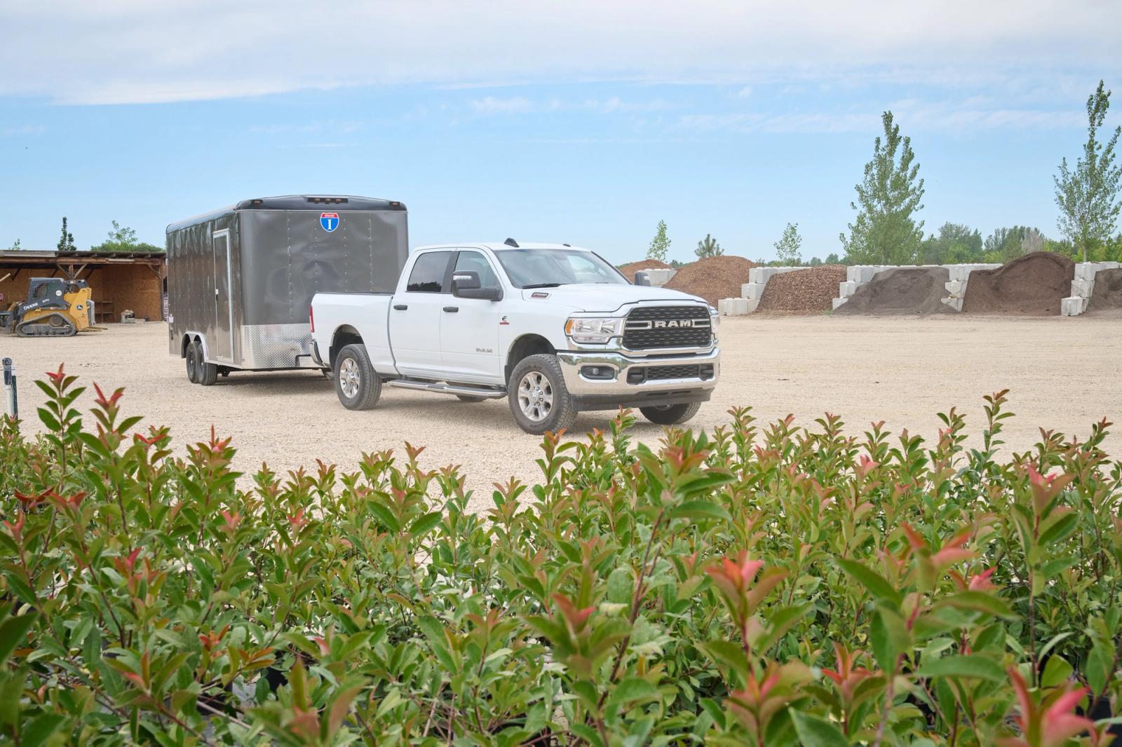 White truck towing a gray trailer, with landscaping material in the background