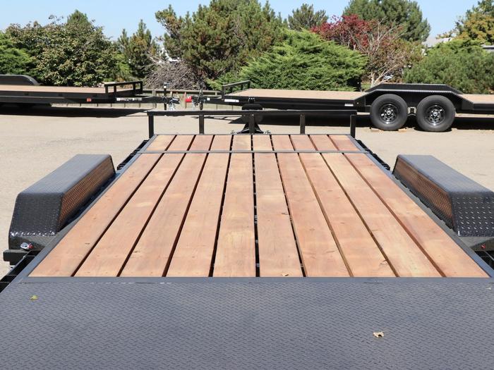 Low-angle view of a black utility trailer's commercial-strength hardwood plank deck and black diamond-plate fender