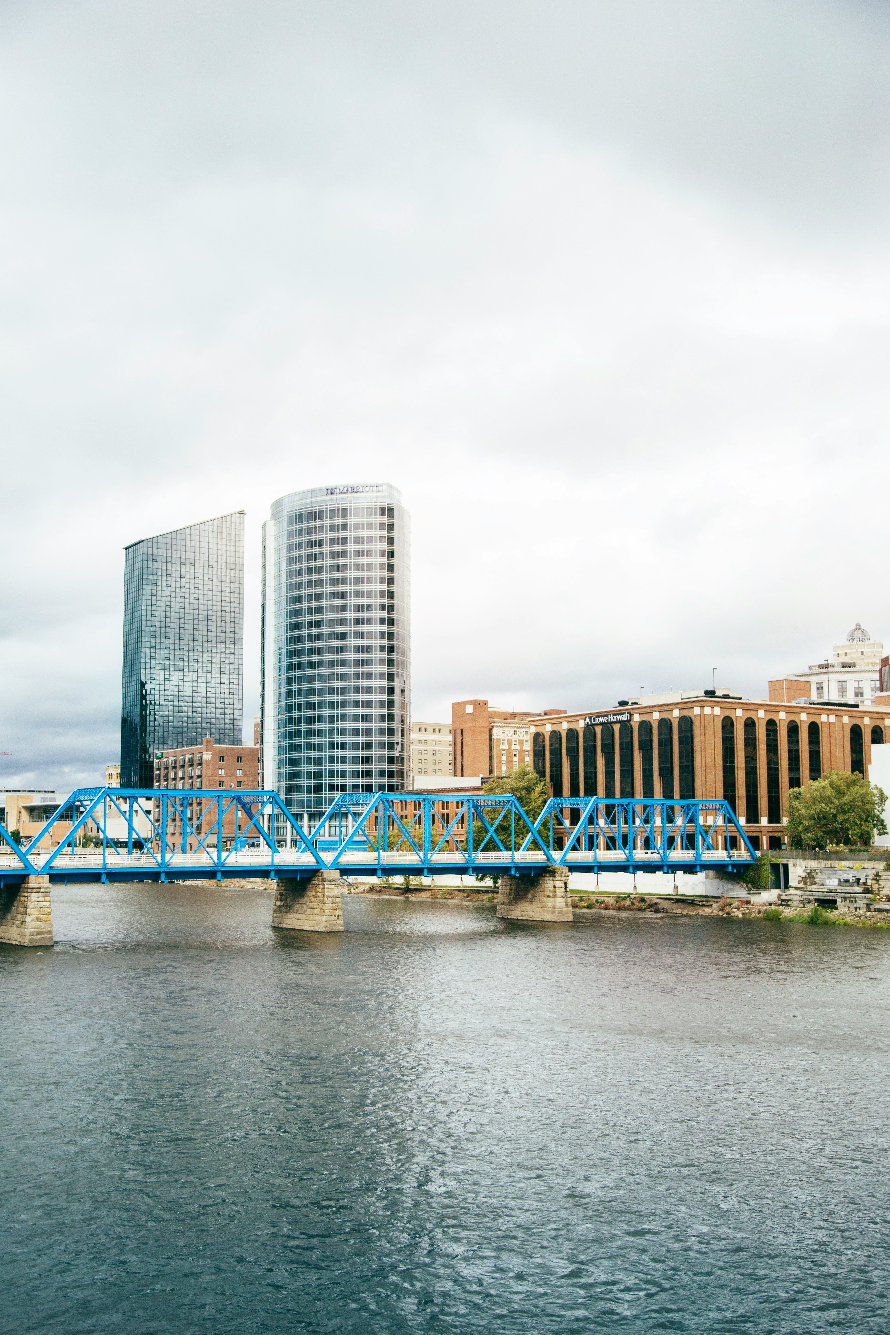 Faded skyline view of Grand Rapids' blue truss pedestrian bridge and downtown high-rises across the river