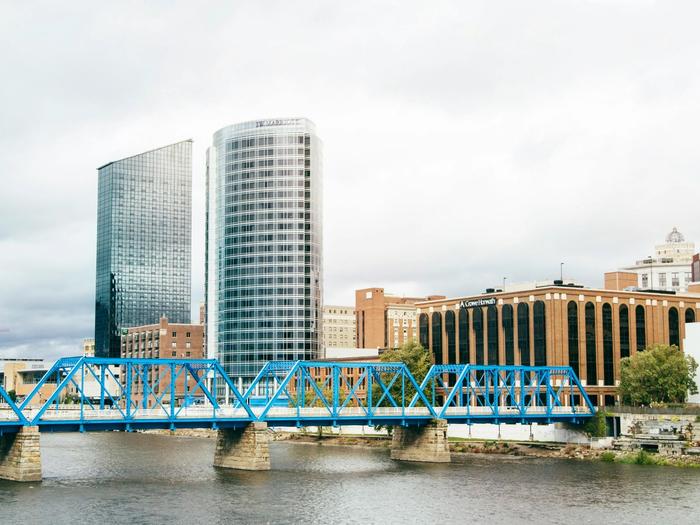 Faded skyline view of Grand Rapids' blue truss pedestrian bridge and downtown high-rises across the river