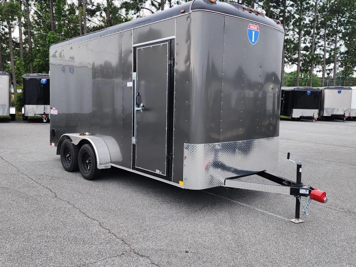 Charcoal Interstate enclosed cargo trailer parked on asphalt at a TrailersPlus lot with white cargo trailers in the background