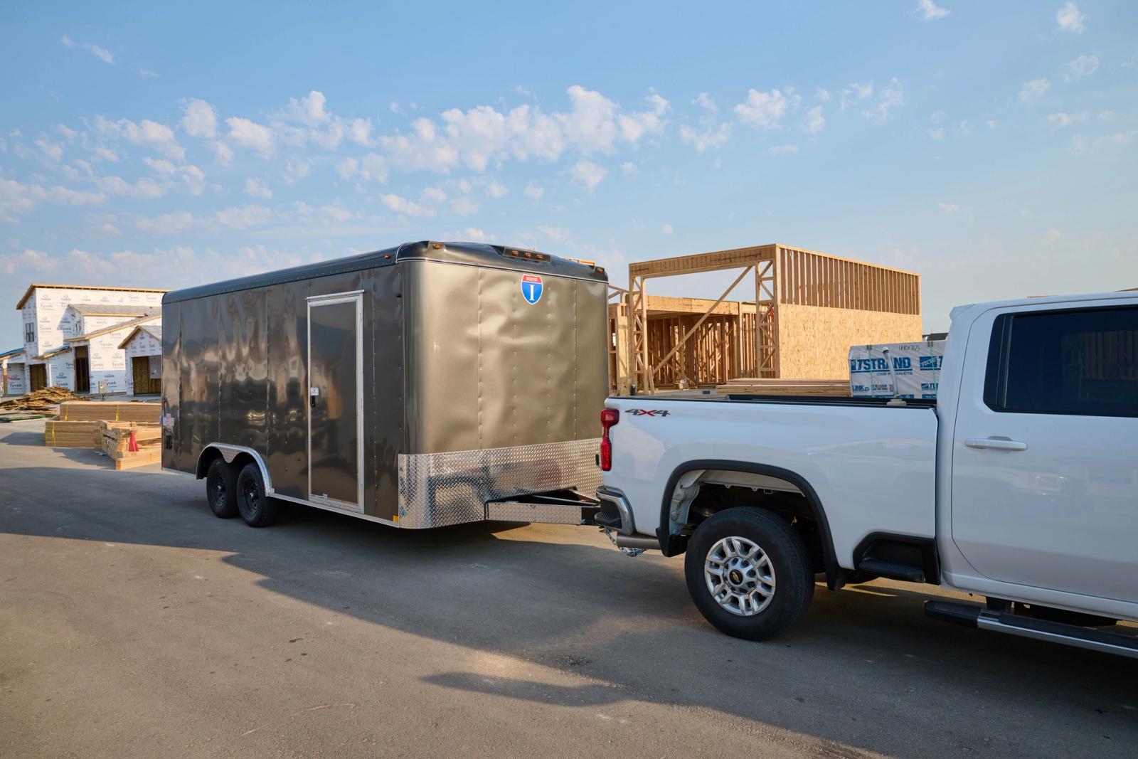 Side view of an Interstate Loadrunner enclosed cargo trailer attached to a white chrevolet truck