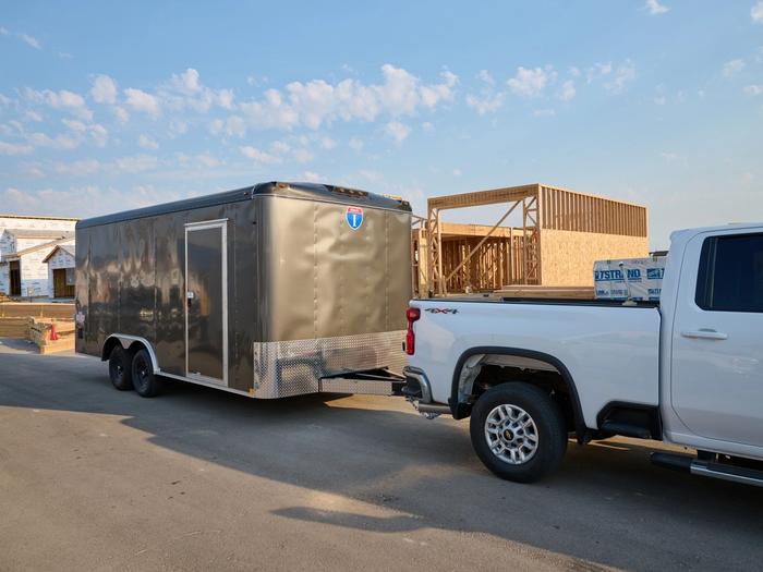 Gray cargo trailer with a side door attached to a white truck