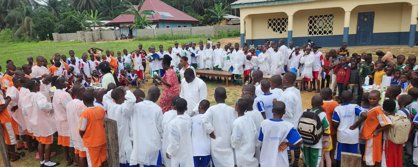 Pupils in lab coats and sports kit gathered in front of the school building