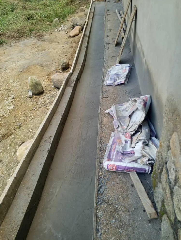 A new concrete drainage channel along the outside of the building