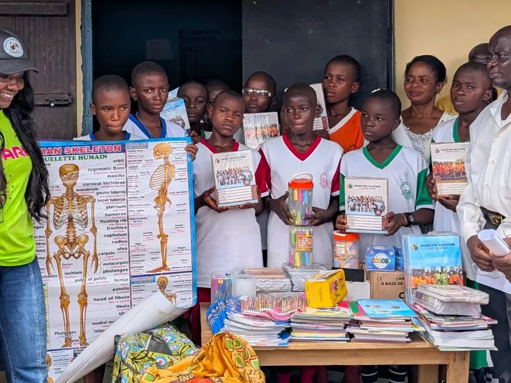 Celebrating the completion: pupils holding new exercise books and a science poster beside a table of school supplies