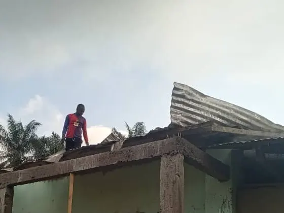 A worker on the school roof lifting off the old corrugated sheets
