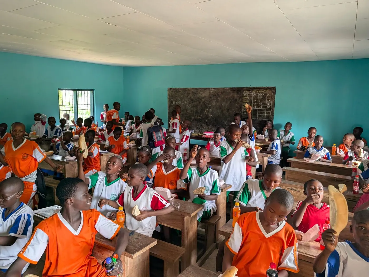 After the rebuild: pupils sharing a meal at their desks in a finished classroom with a new ceiling and freshly painted walls