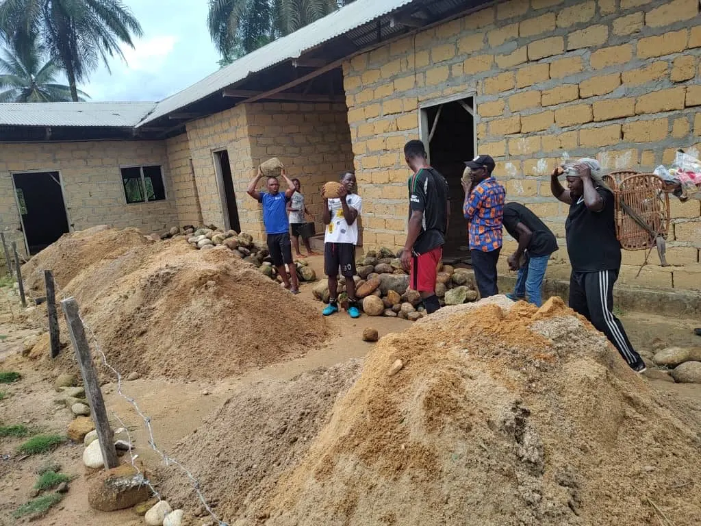 Families carrying stones and sand alongside the builders