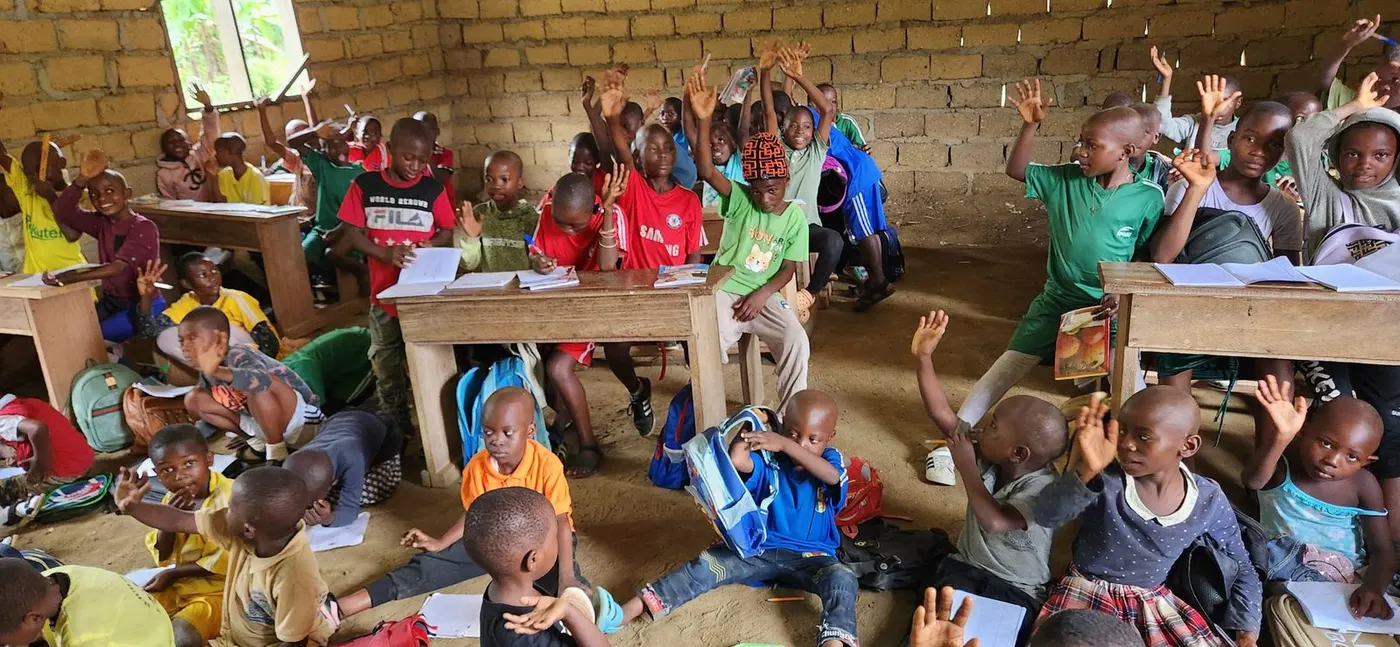 Before: a crowded classroom with an earth floor and bare brick walls