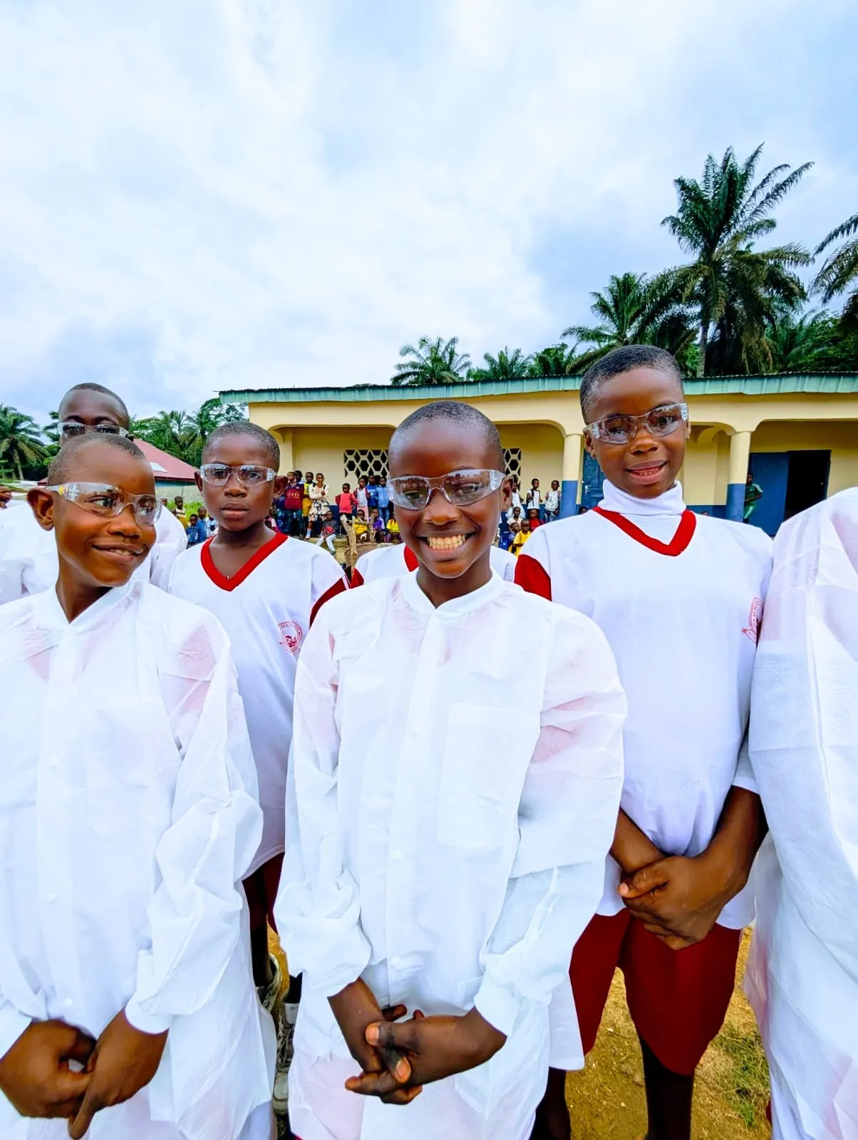 Smiling pupils in white lab coats and safety glasses