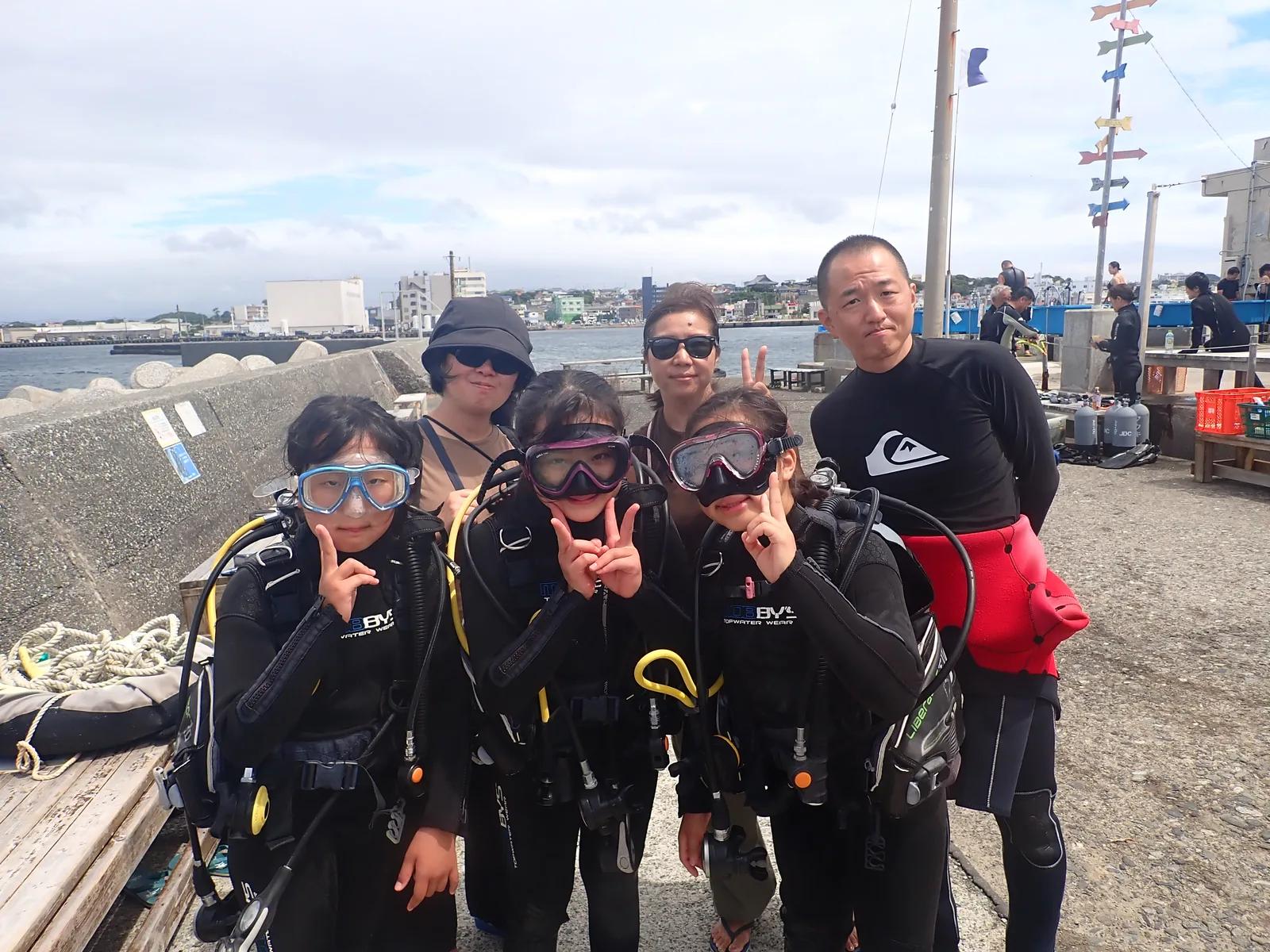 城ヶ島でJr.体験ダイビングに参加した子どもたちと、器材を背負って笑顔の記念写真