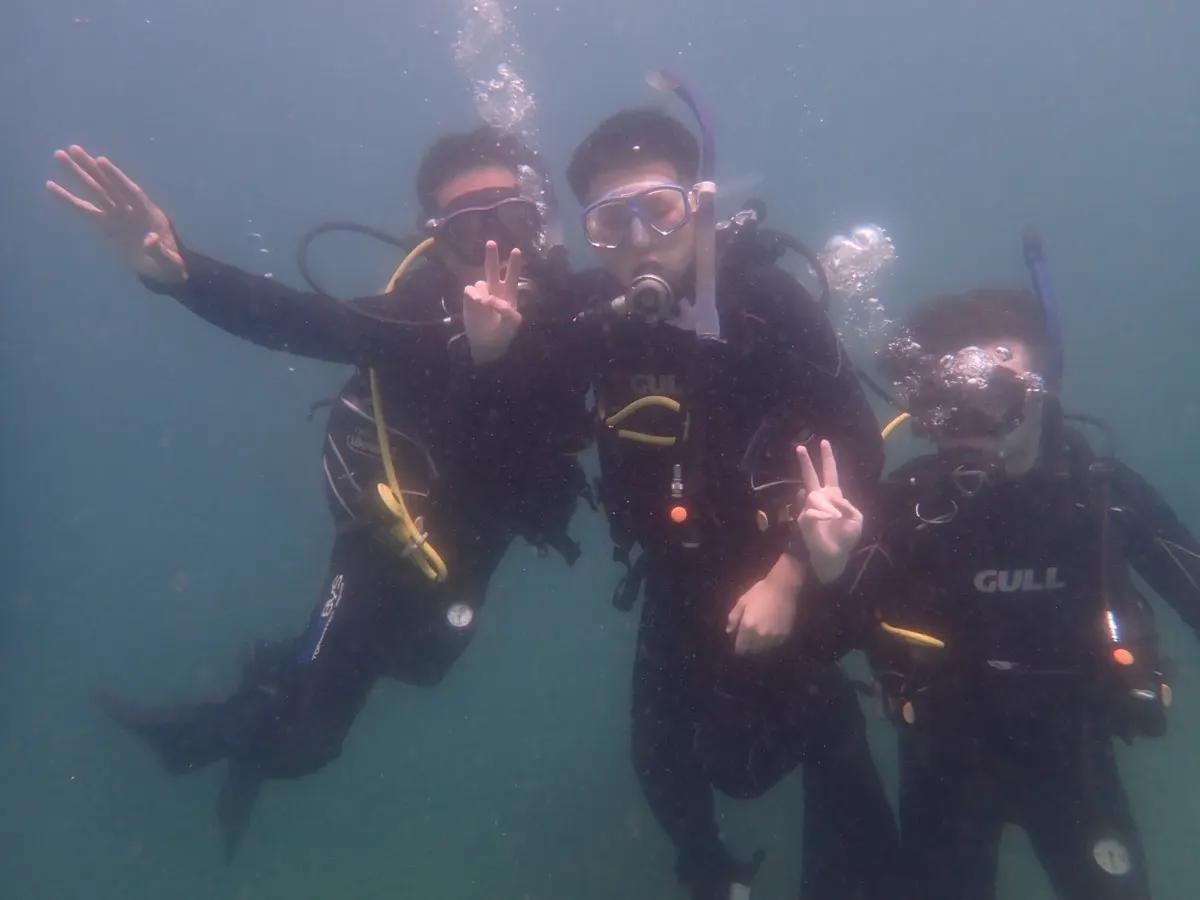 三浦の海の中で並ぶアドバンス講習中の親子3名のダイバー