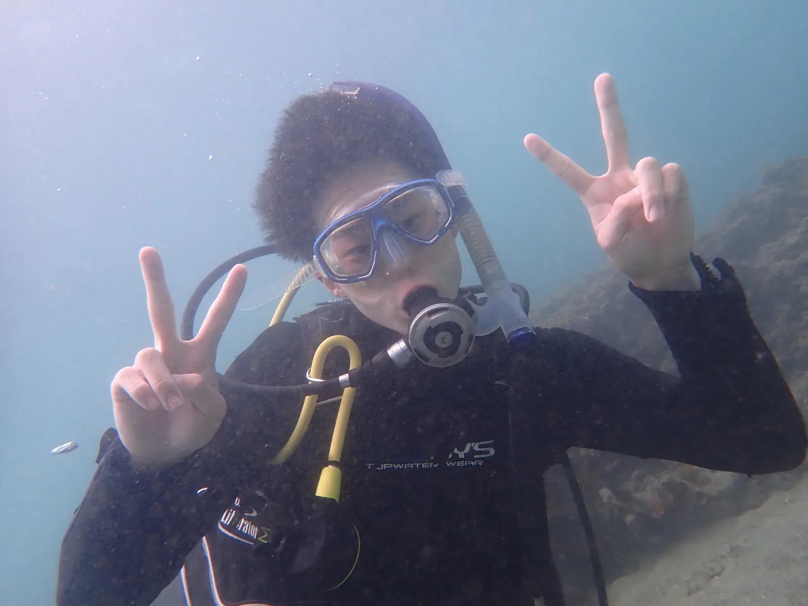 三浦の海の中でピースサインを出す体験ダイビング中のお客様