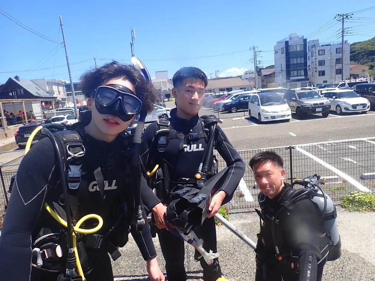 器材を背負って海洋実習に向かう三浦 海の学校のダイビングライセンス講習の受講生