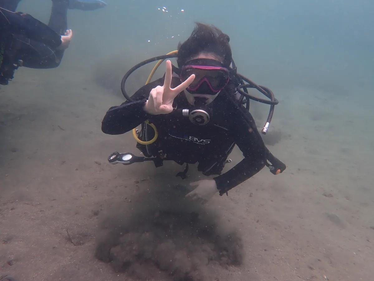 城ヶ島の海底でピースサインを見せる体験ダイビング中のダイバー