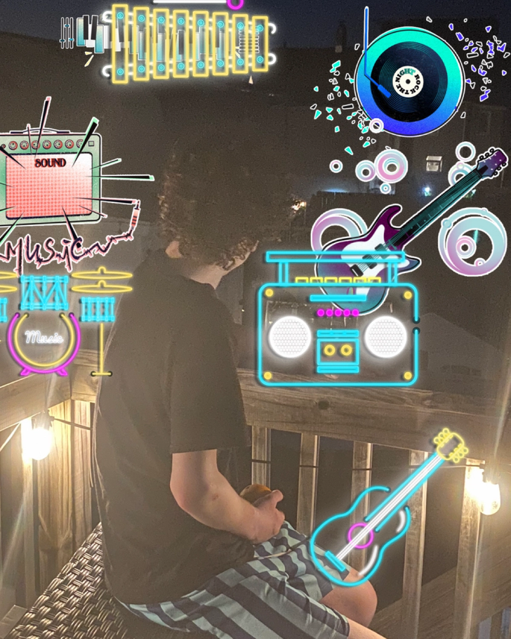 A young boy sitting on a deck at night, surrounded by colorful music-themed graphics, including musical instruments and sound symbols. He appears relaxed, holding a snack, and is enjoying the evening ambiance.