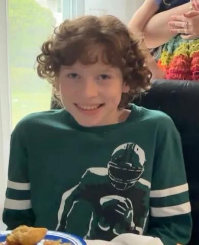 Halen, Tracie Smith's son, smiling while wearing a green football-themed shirt, celebrating his 13th birthday at a family gathering.