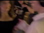 A blurry image of a mom and her son dancing together at a lively outdoor event, surrounded by others enjoying the music. The atmosphere is joyful and energetic, capturing a moment of connection.