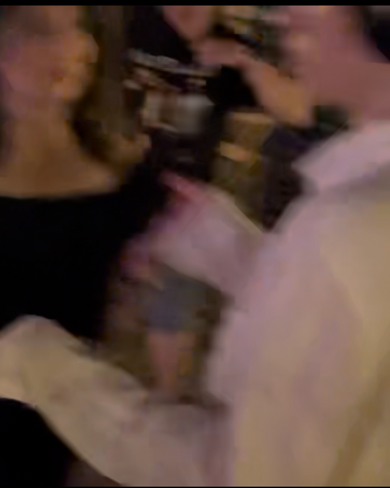 A blurry image of a mom and her son dancing together at a lively outdoor event, surrounded by others enjoying the music. The atmosphere is joyful and energetic, capturing a moment of connection.