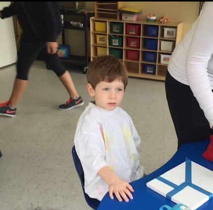 Halen, Tracie's young child, sitting at a table in a classroom, engaged in an activity.