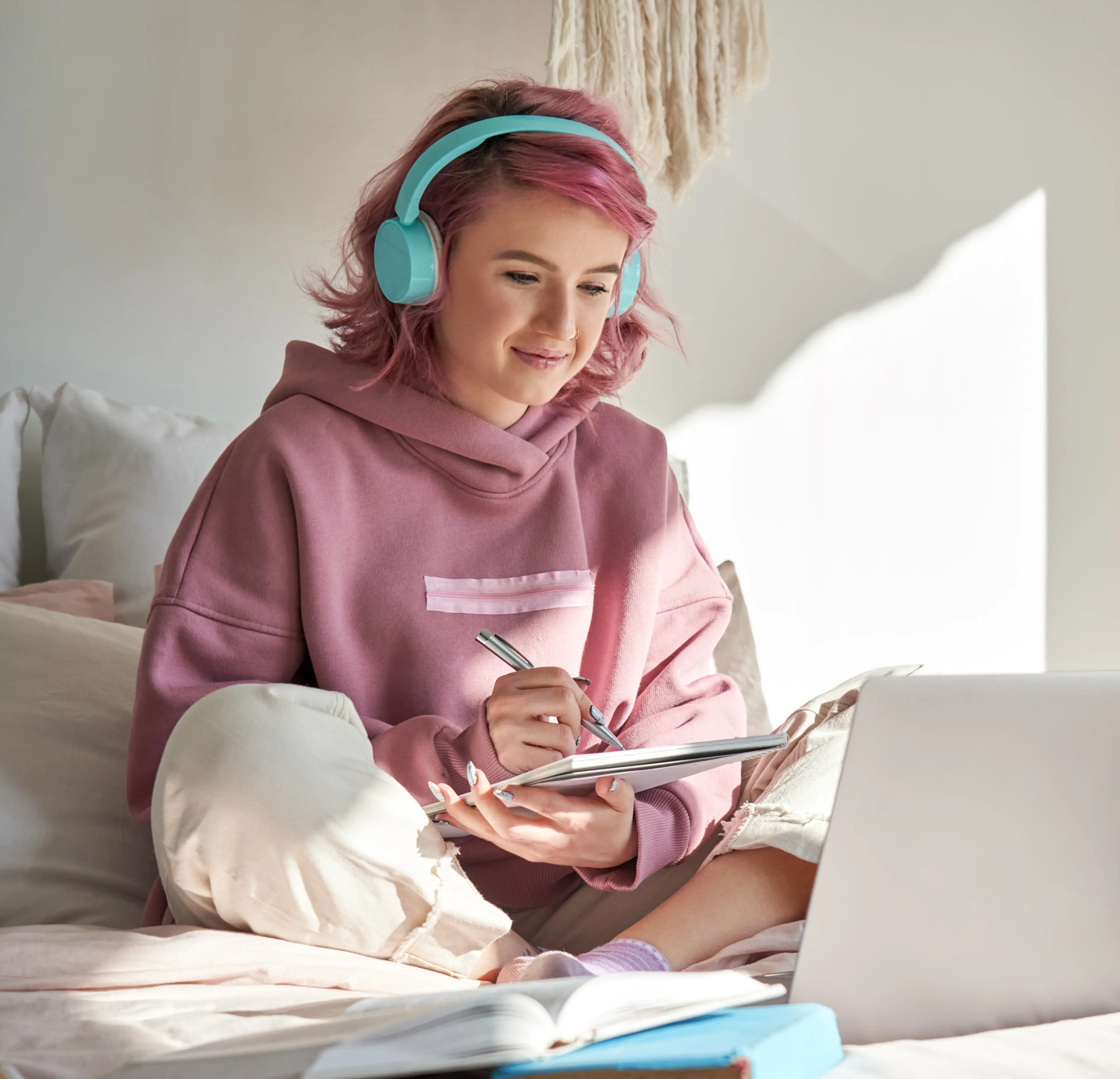 Young lady in pink, sitting on her bed and working