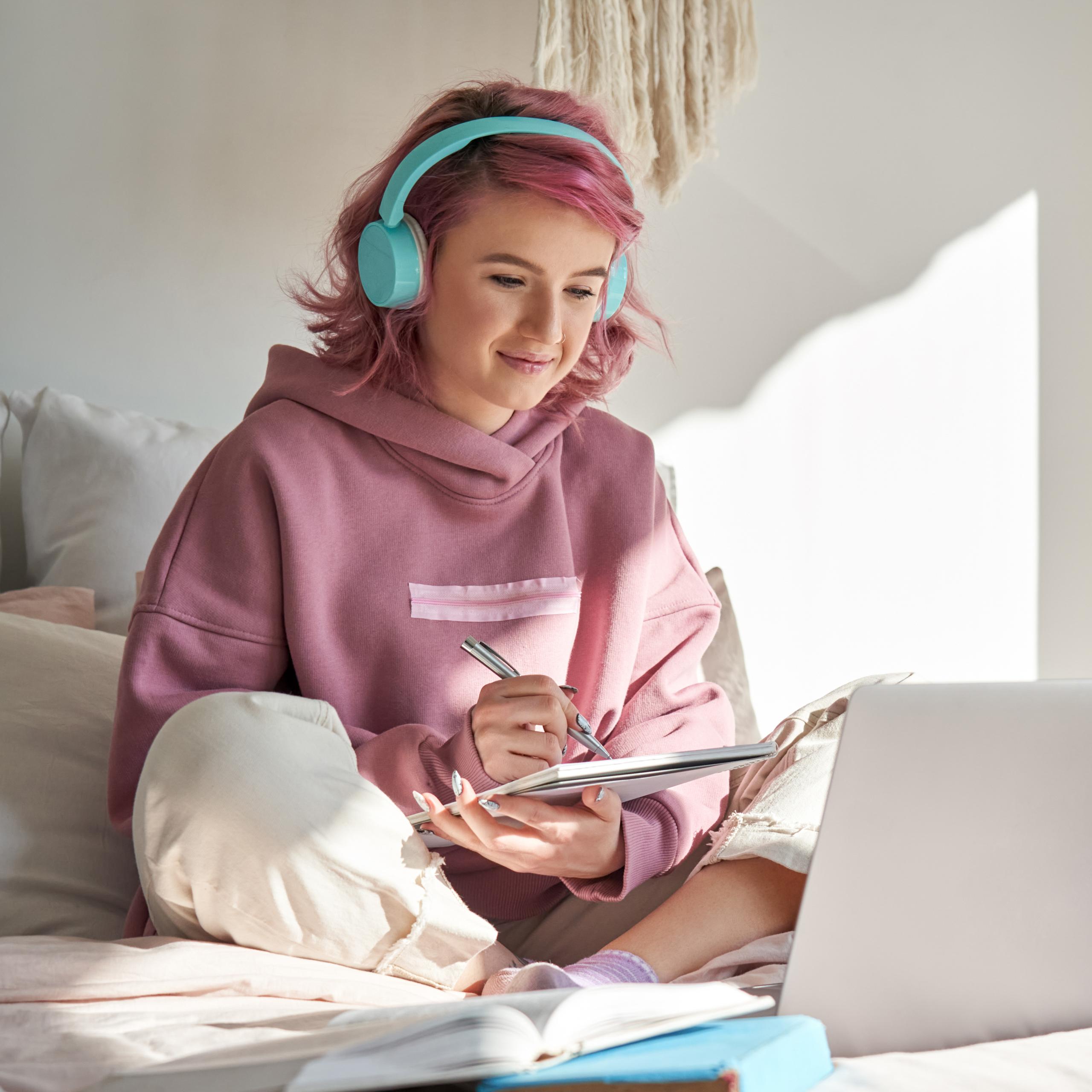 Young lady in pink, sitting on her bed and working