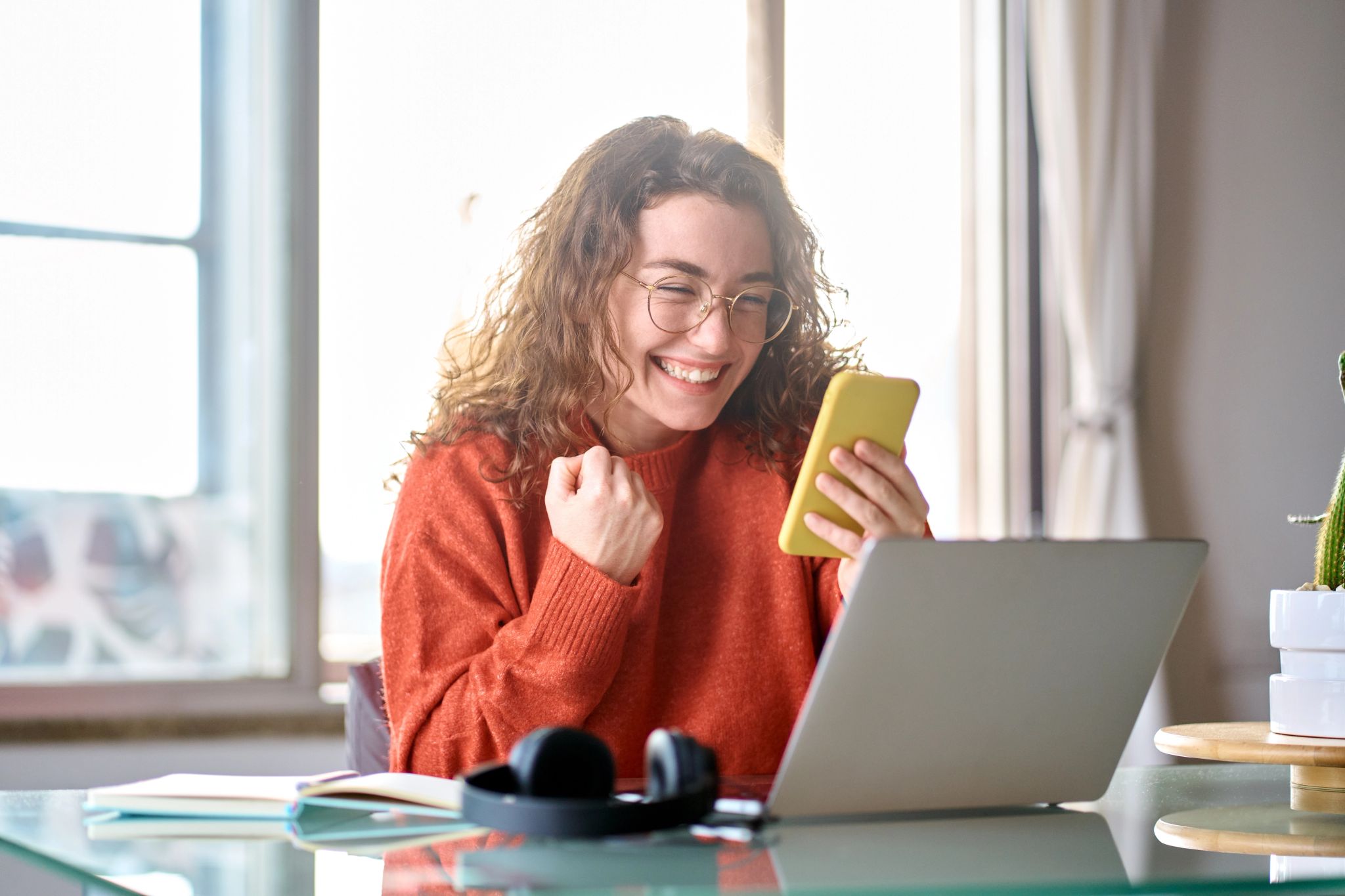 Woman at home happy that her loan has been approved as she checks her mobile