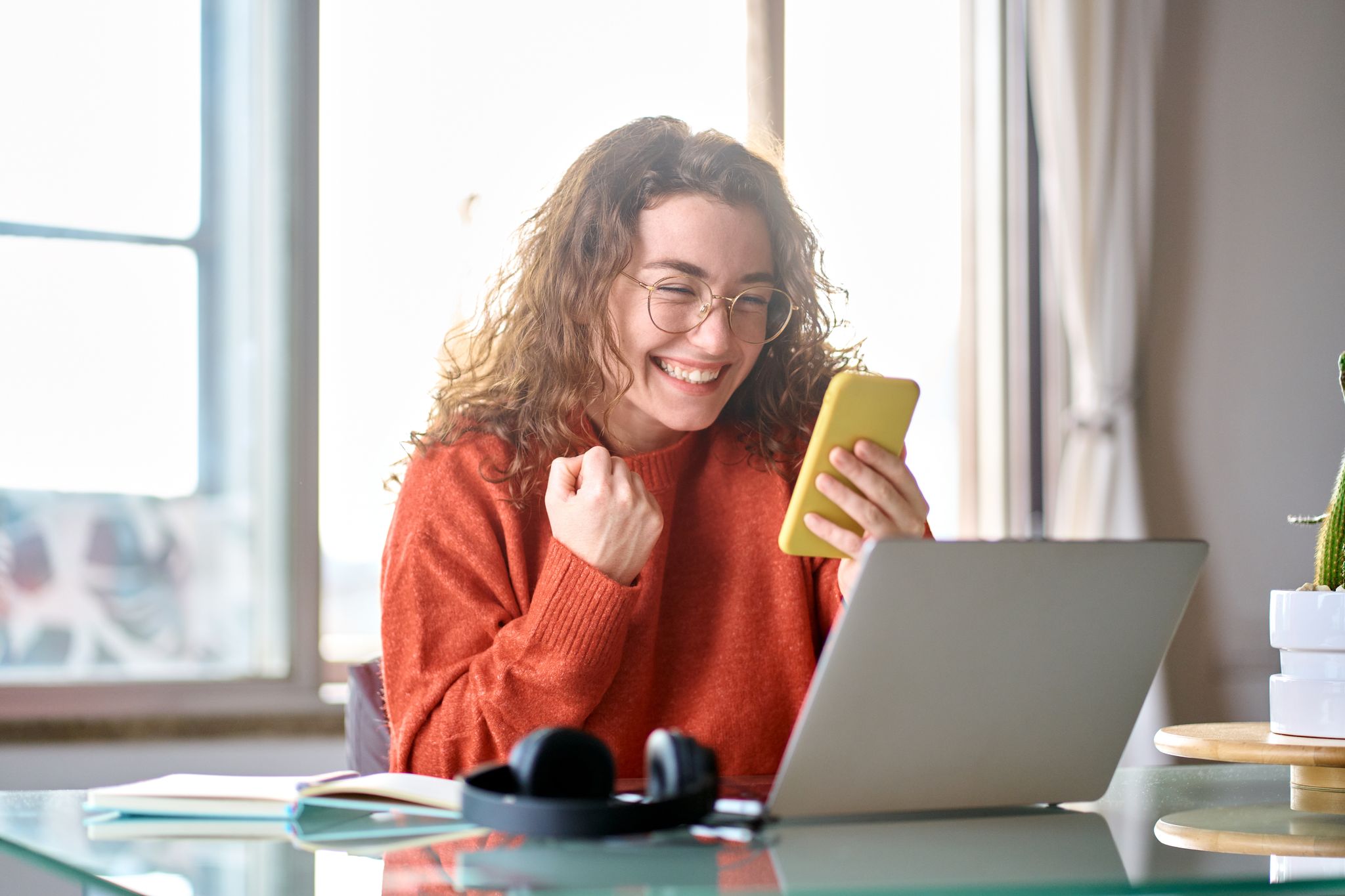 Woman at home happy that her loan has been approved as she checks her mobile