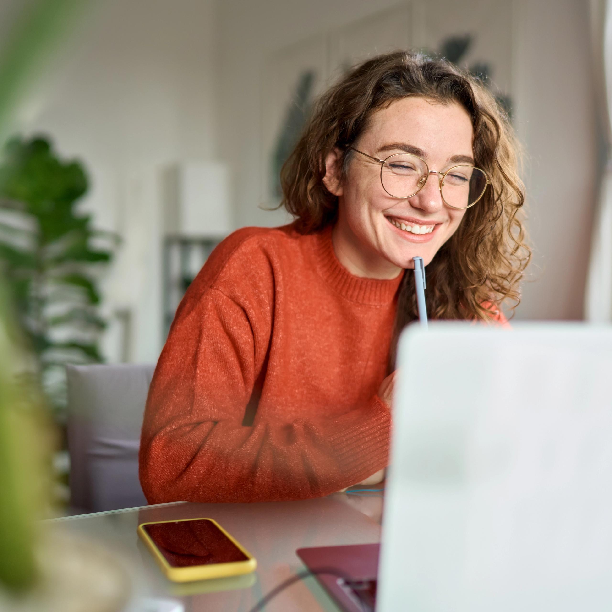 Young woman smiling as she checks her laptop