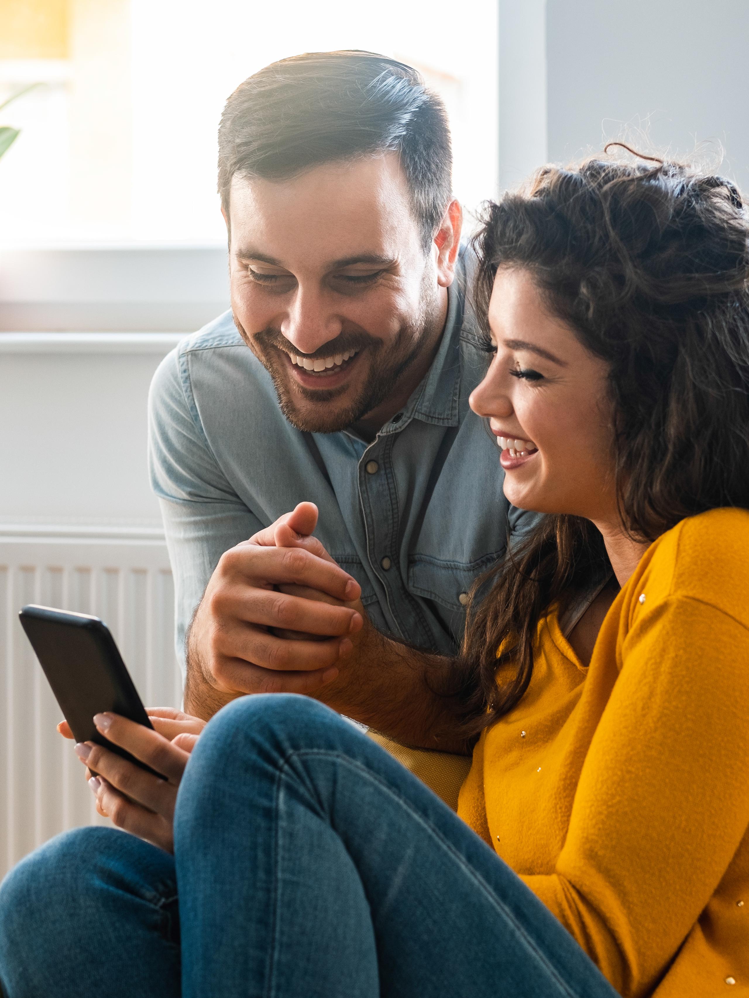 A couple at home checking their loan results on their mobile phone