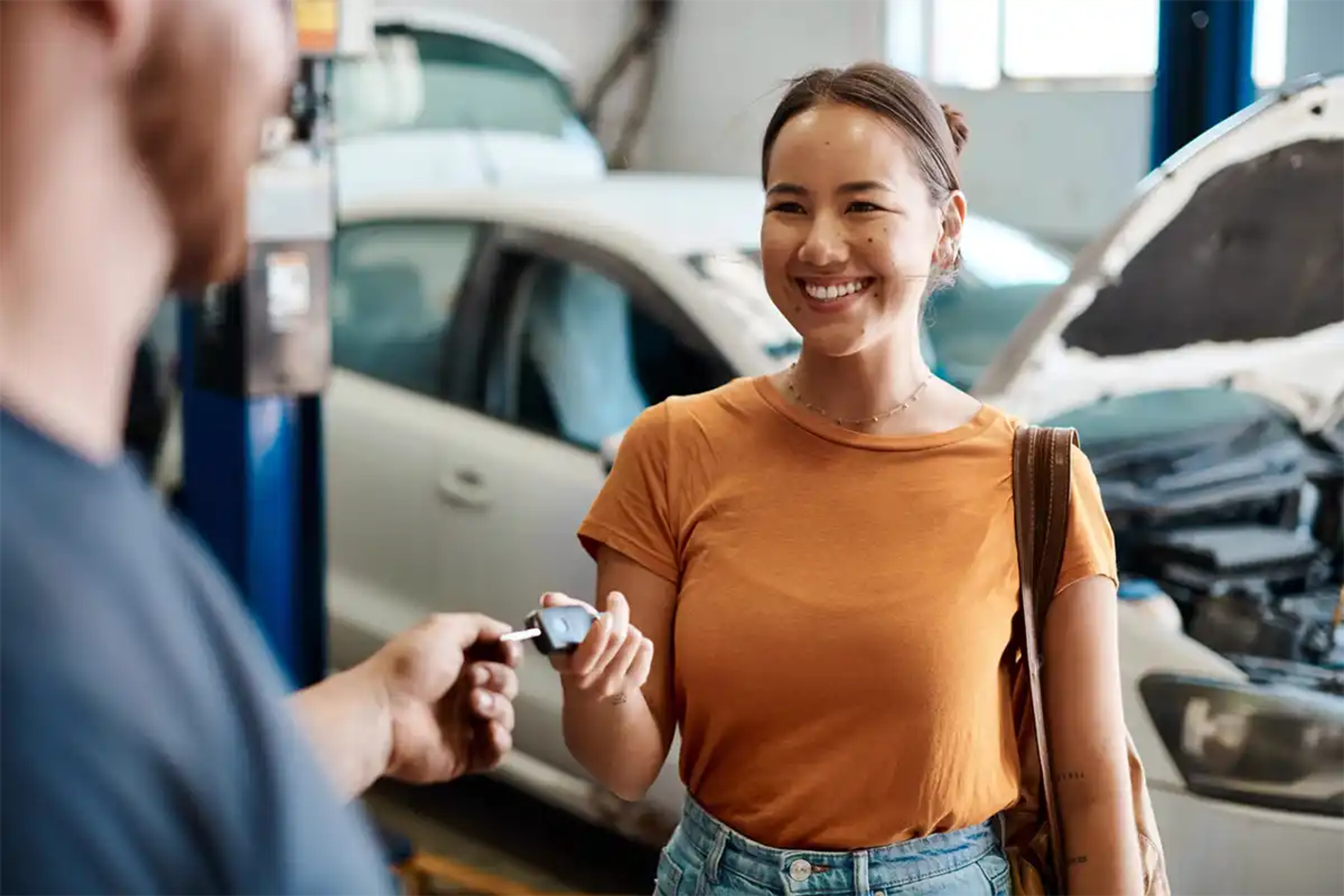 Young woman smiling as she picks up her car from the garage repair shop