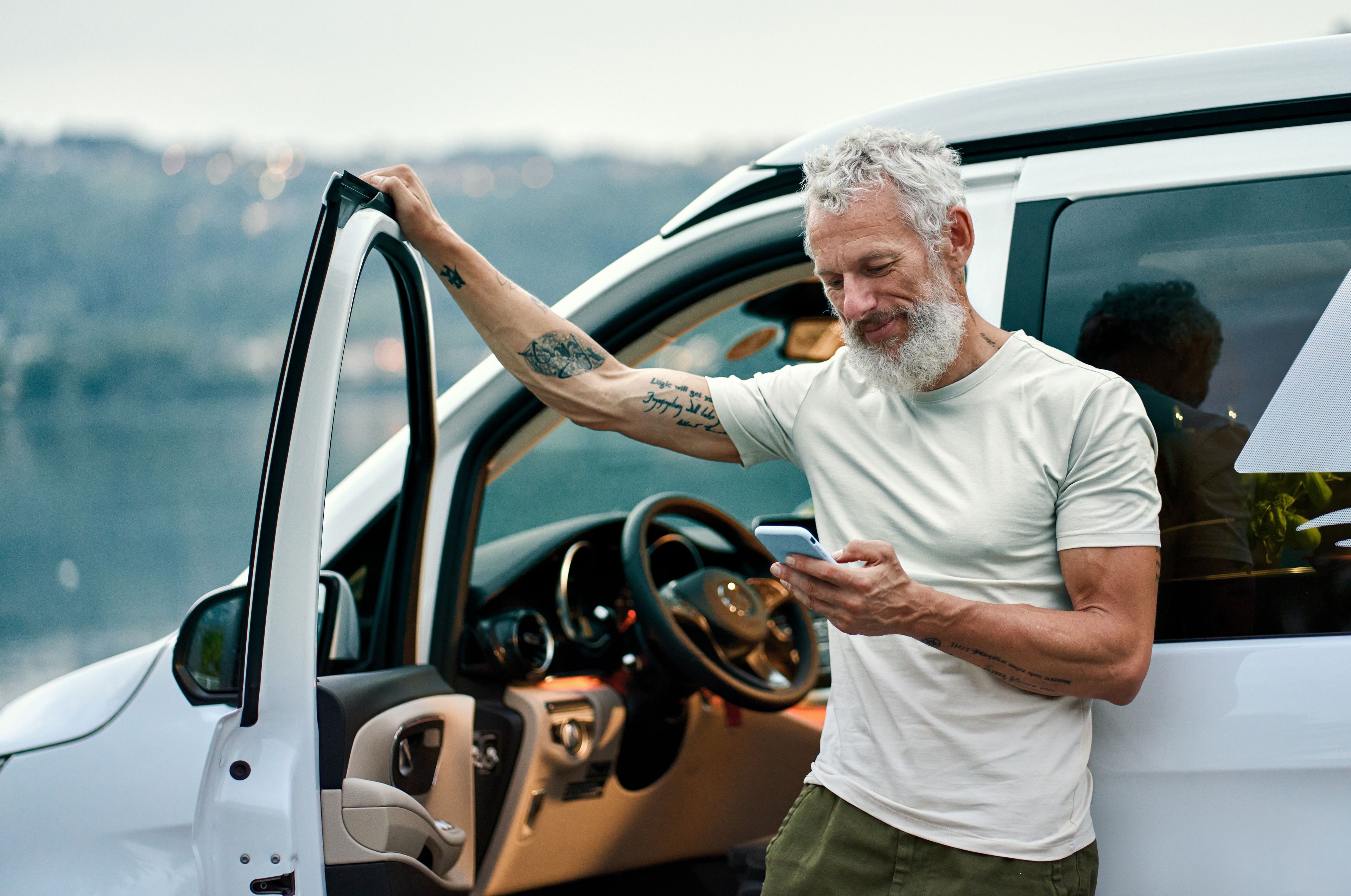 Man with his car door open and checking his mobile.