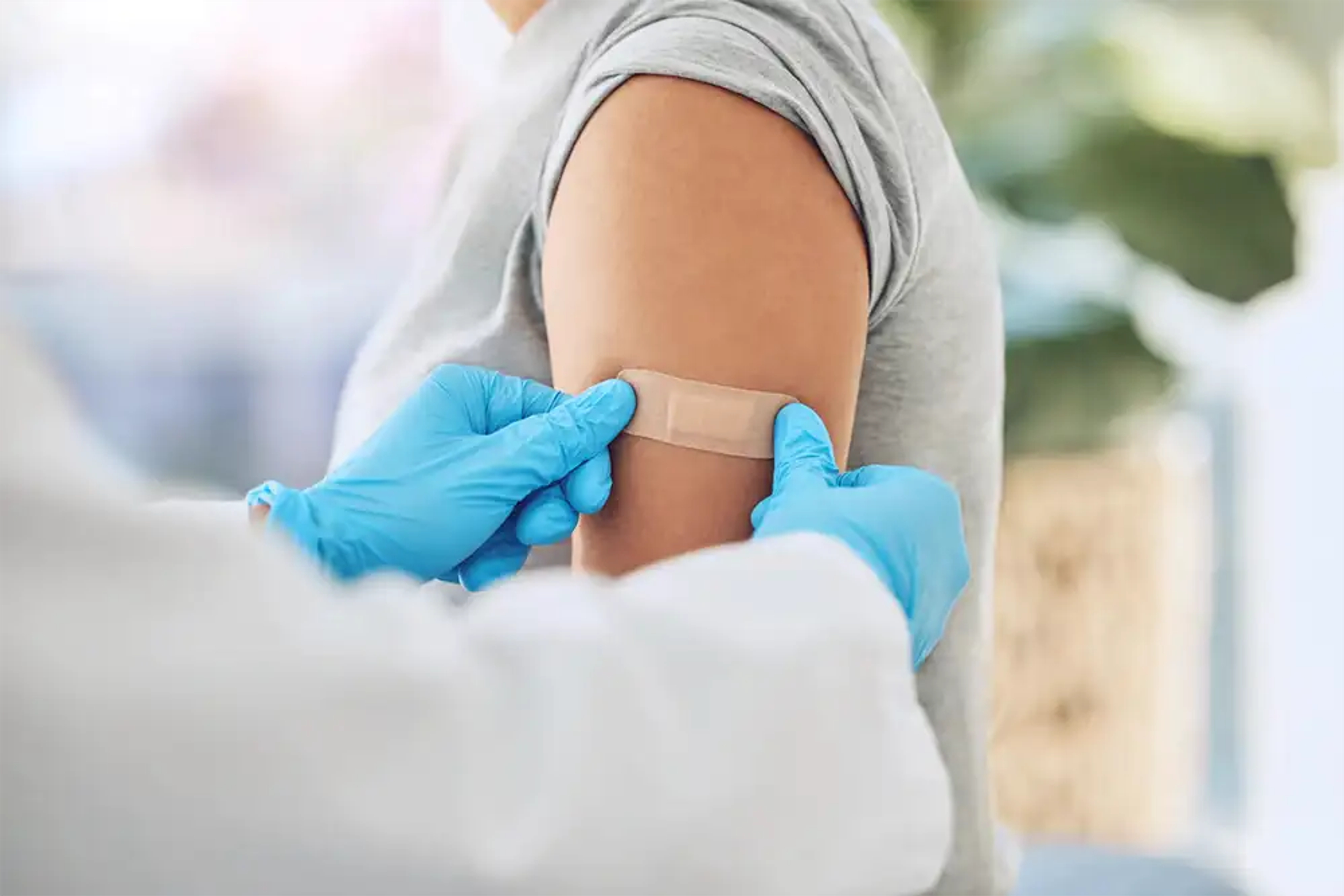 Woman getting a medical plaster placed on her arm by a nurse