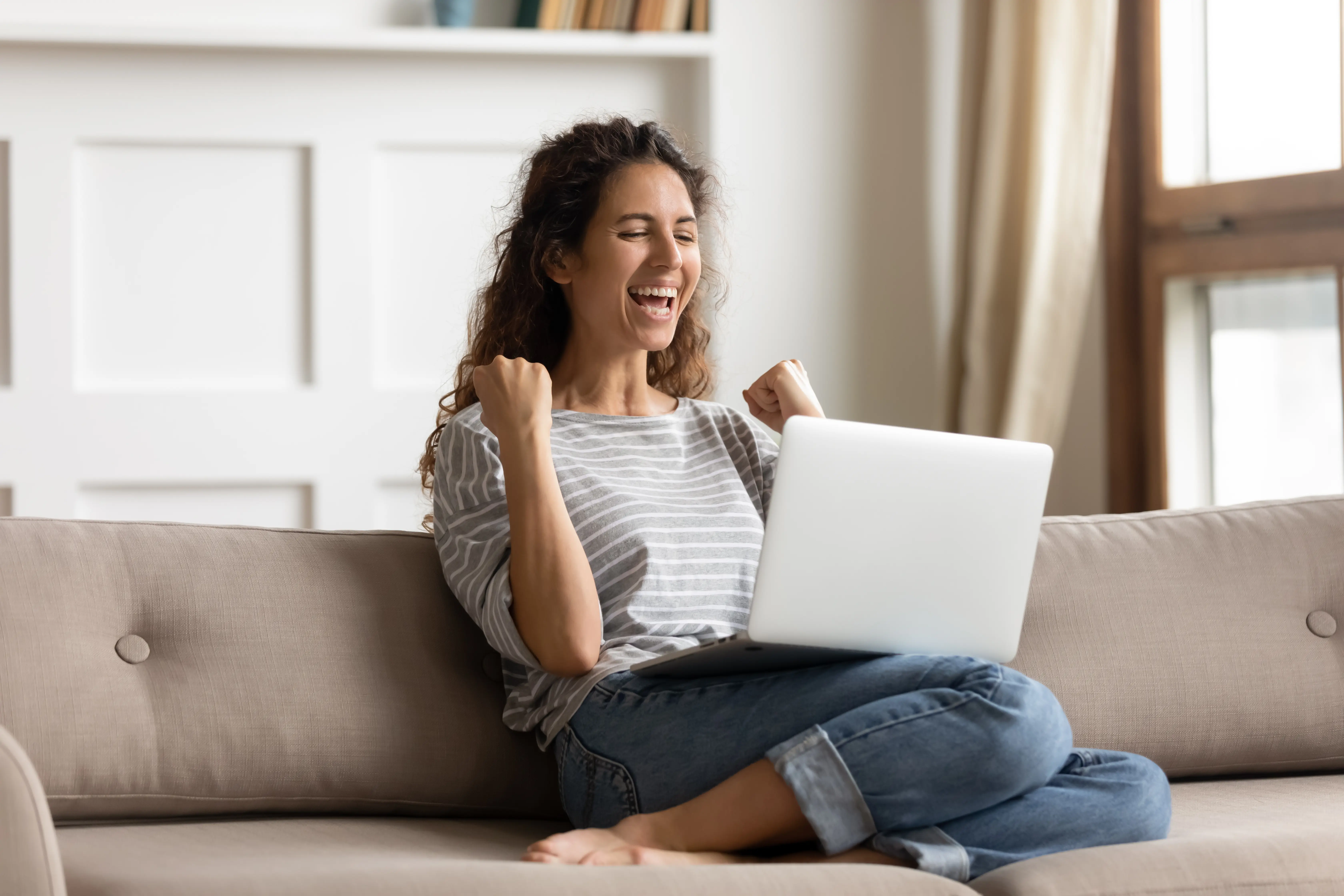 Happy woman sitting on her sofa with her laptop