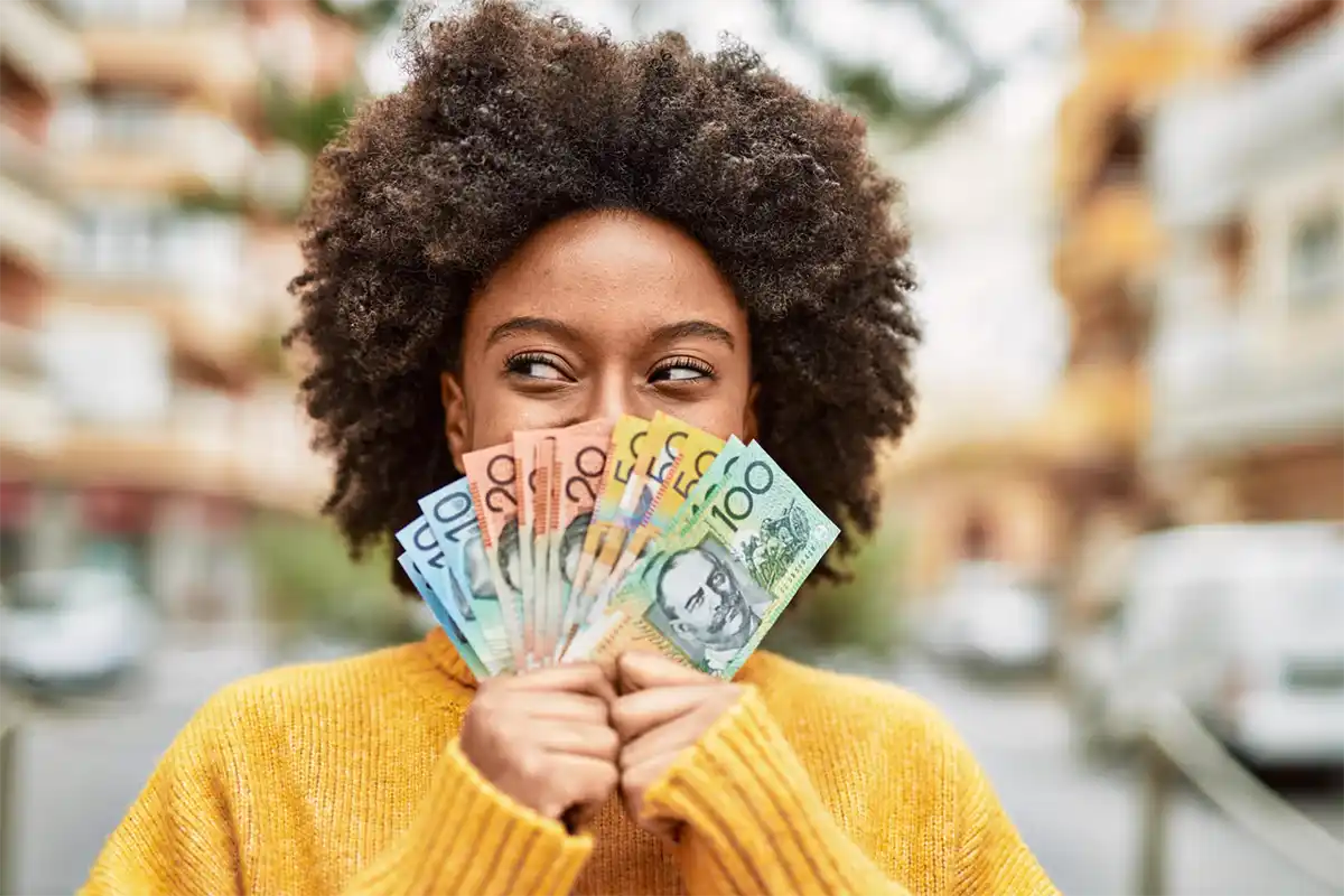 Young happy woman holding a fan of Australian dollars