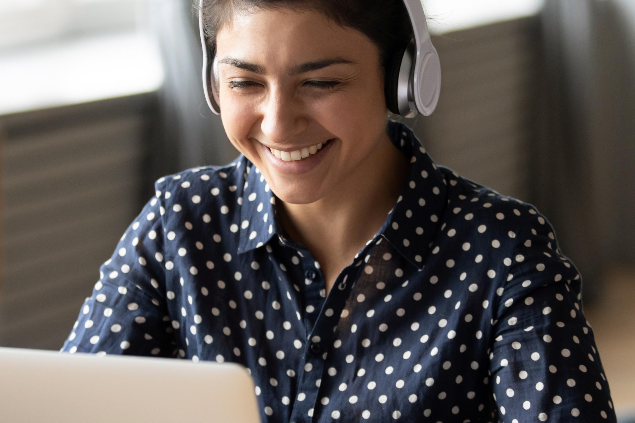Woman in spotted shirt uses her laptop