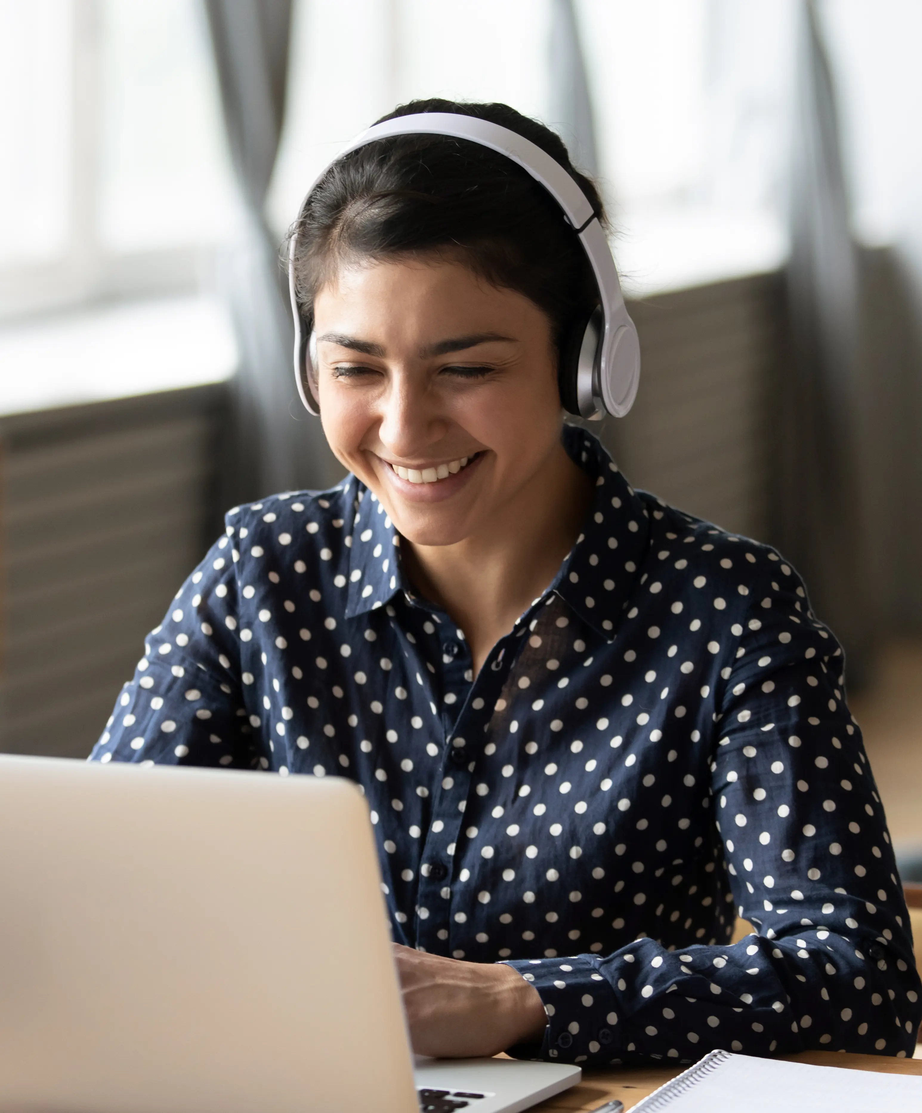 Woman in spotted shirt uses her laptop