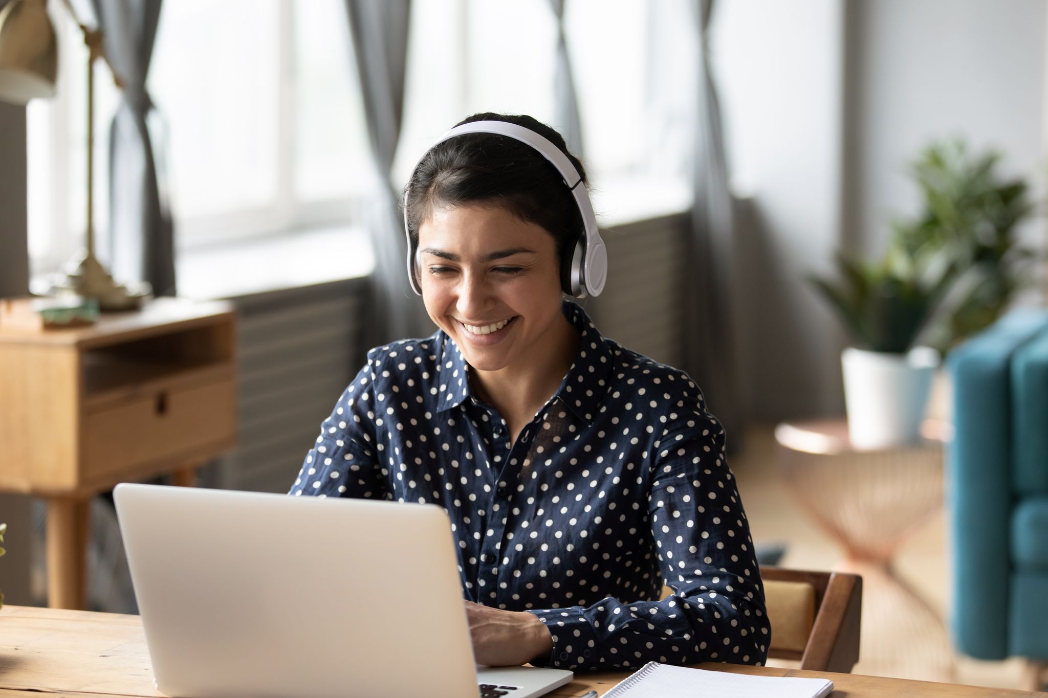 Young women with earphones checking her laptop at home