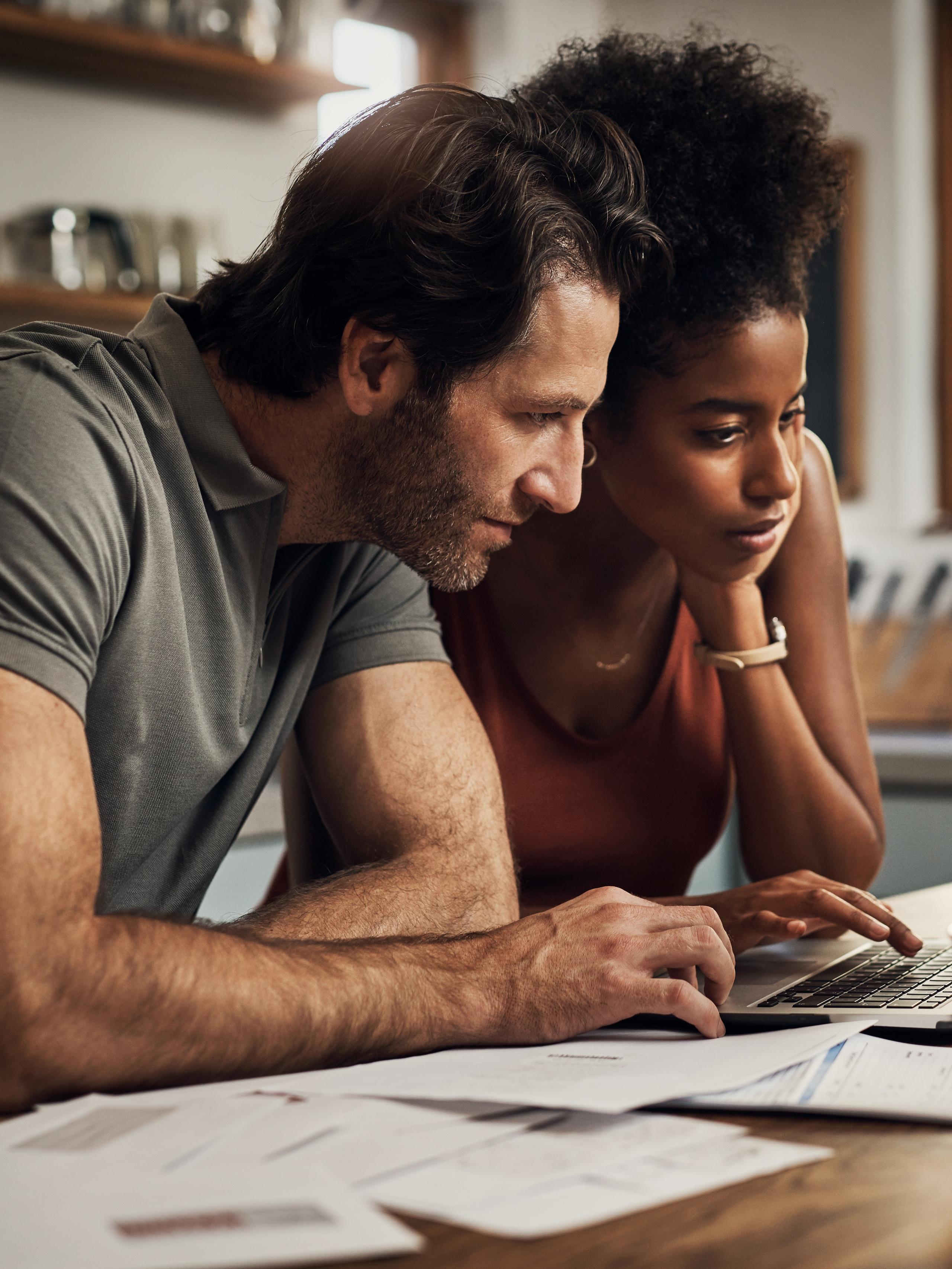 A couple at home checking their financial paperwork and checking on their laptop