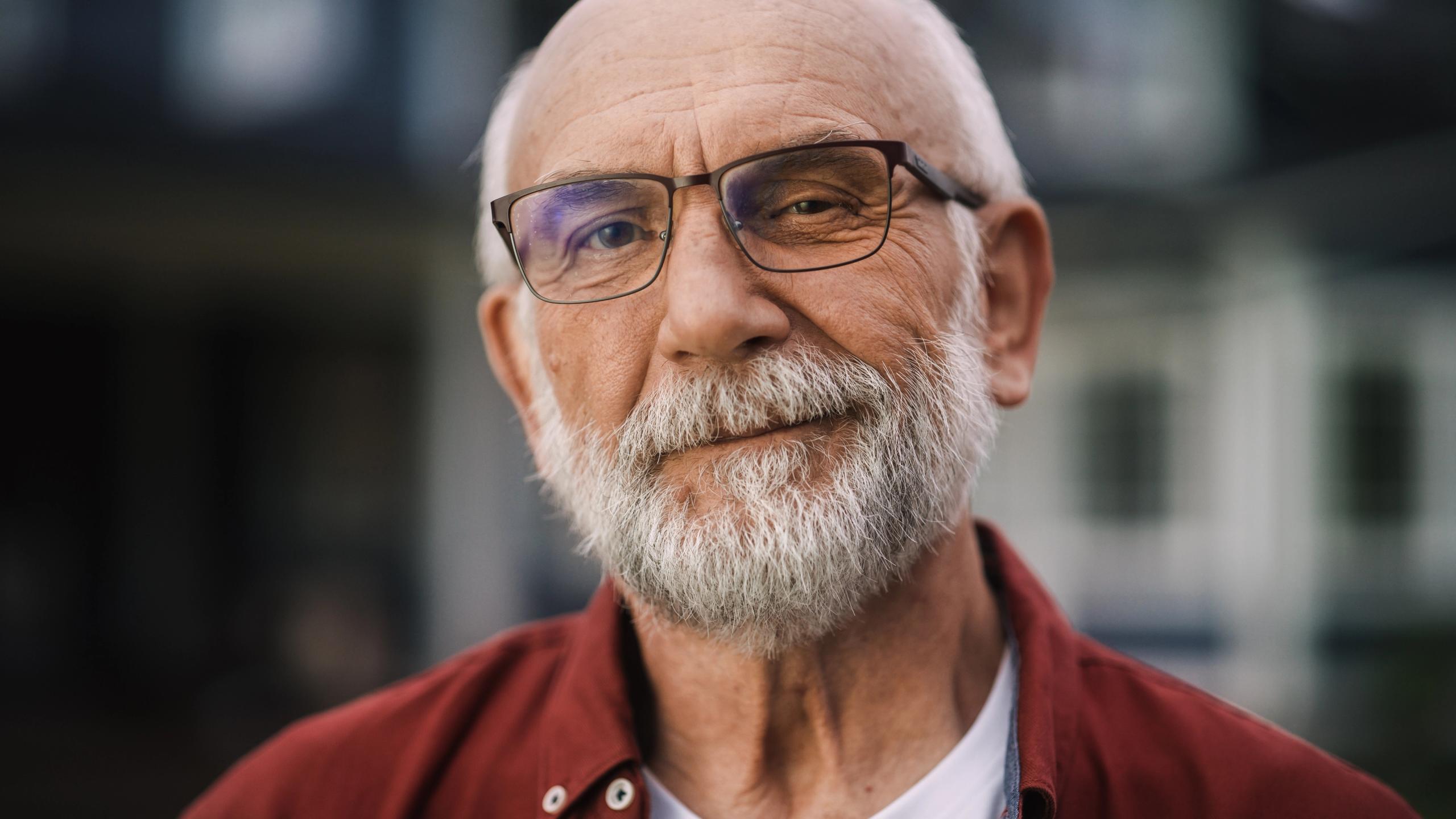A smiling older man with white beard and glasses