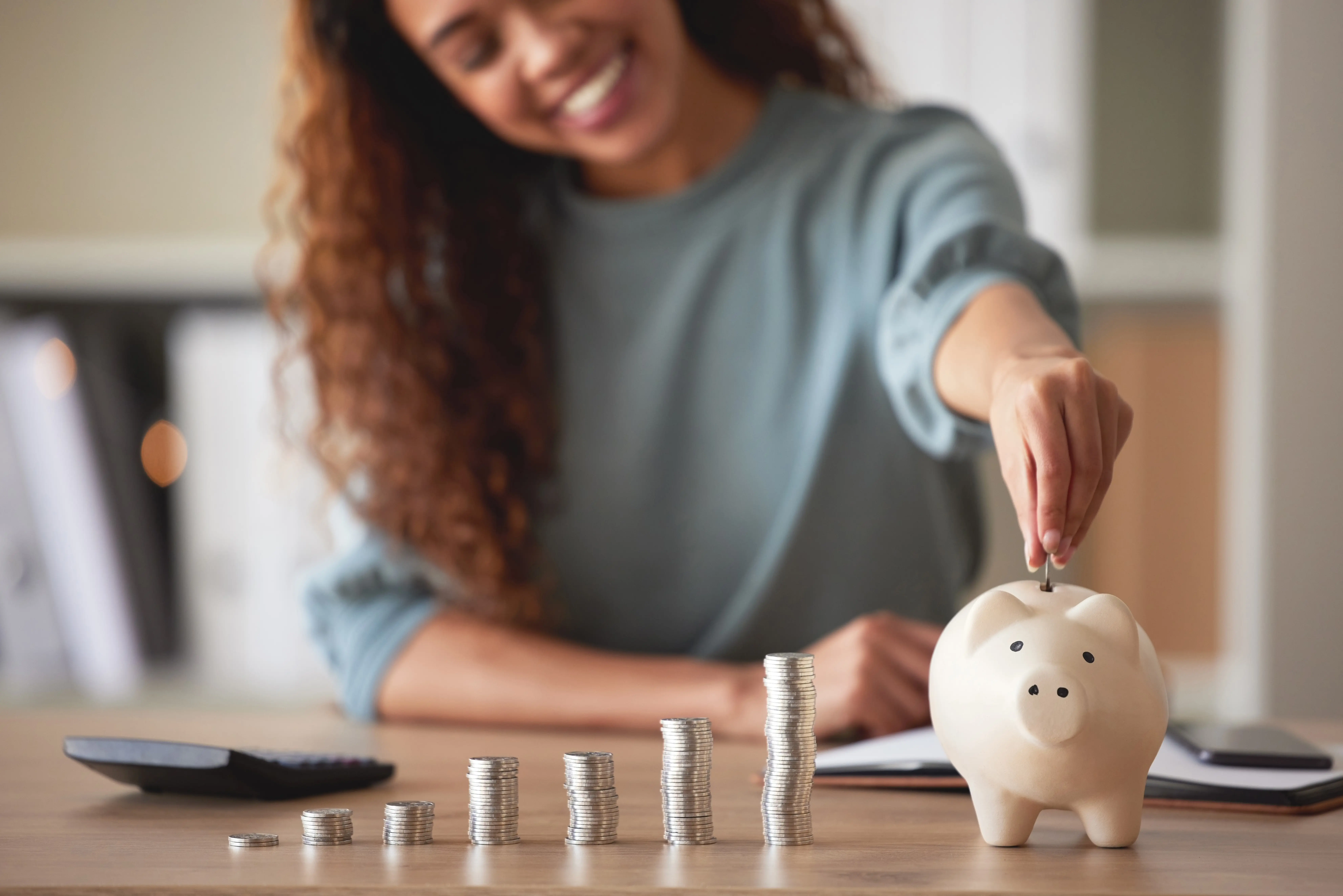 A woman at home putting change in her piggybank