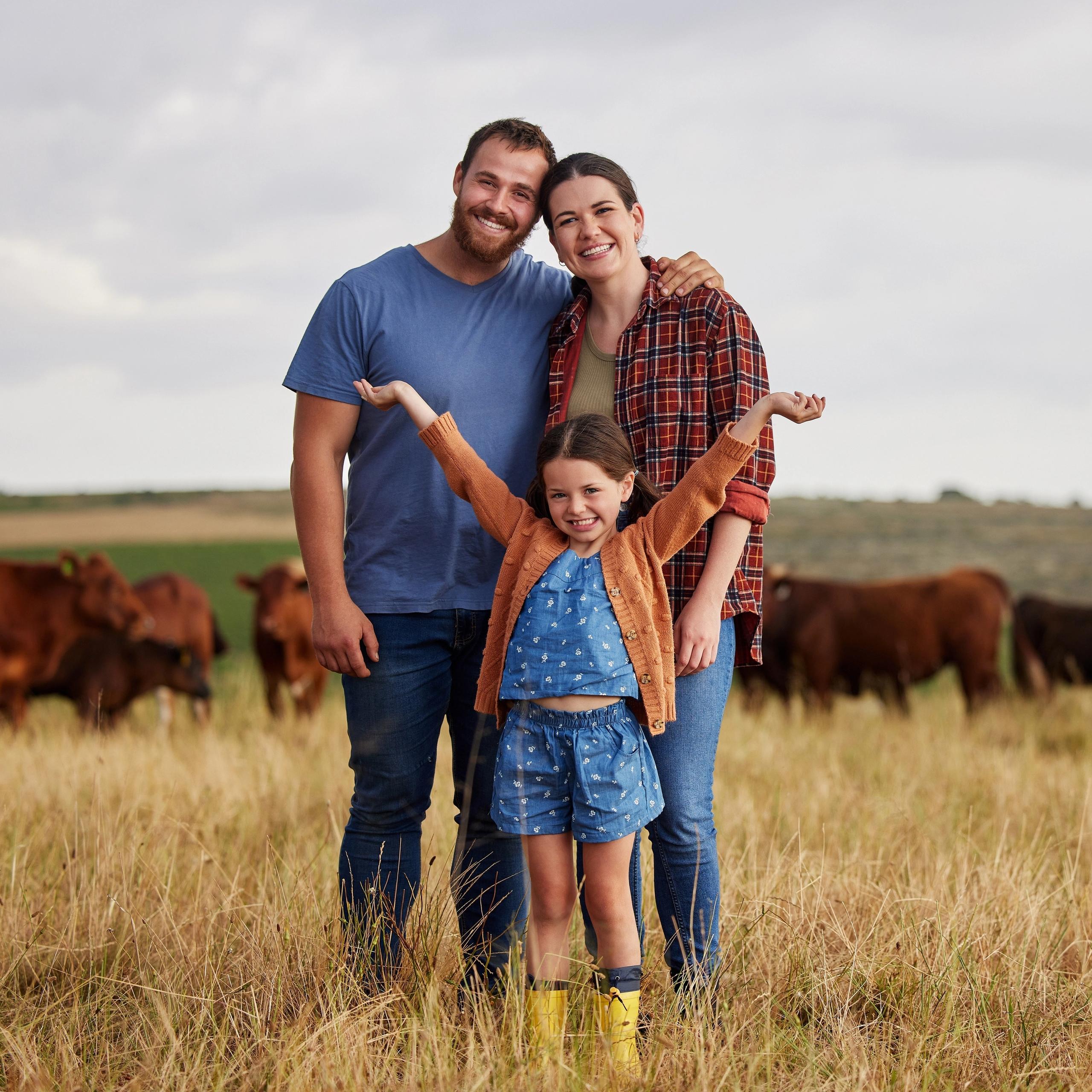 Happy family in a field with cows in the background