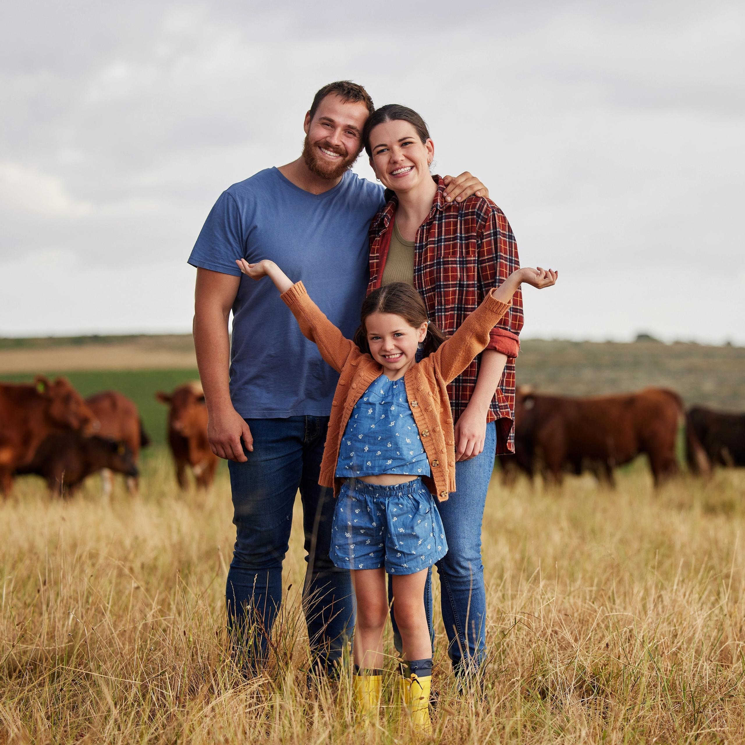 A couple with their daughter in front of them, standing in a field