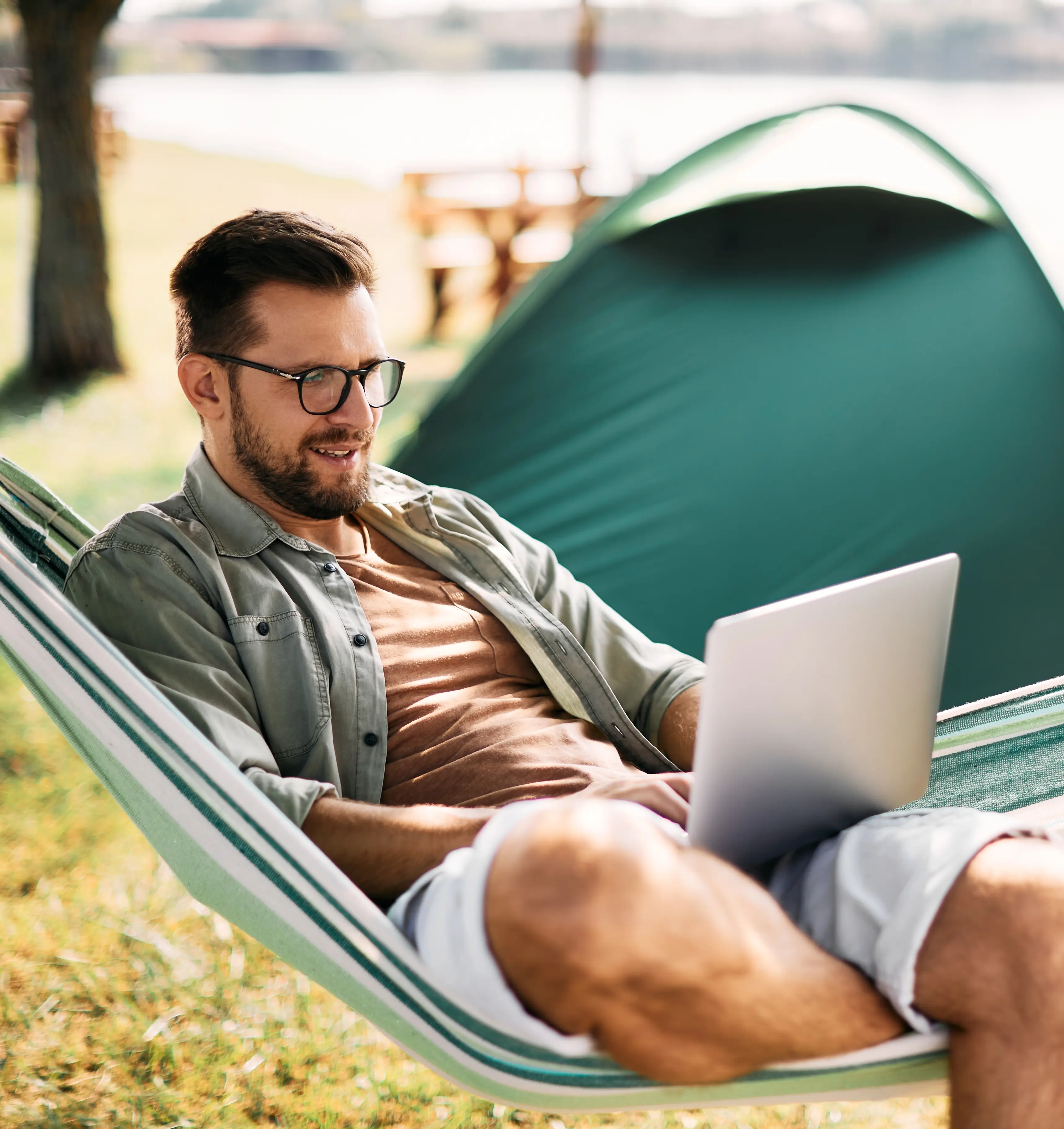 Man reclining in hammock and checking his laptop