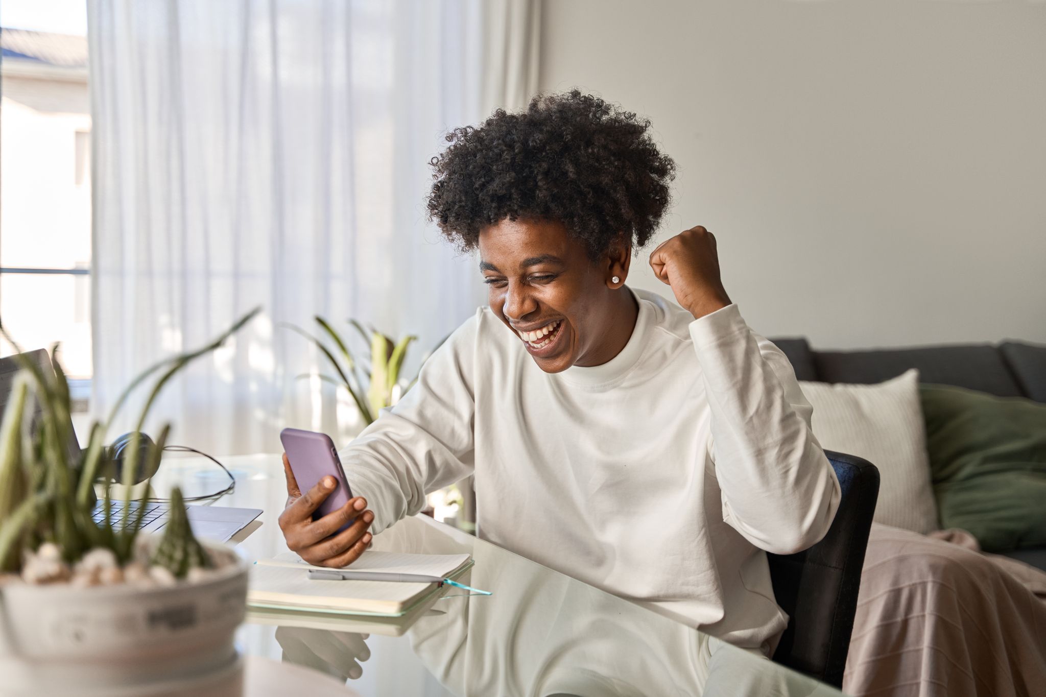 Young African person at home checking their loan application status on their phone