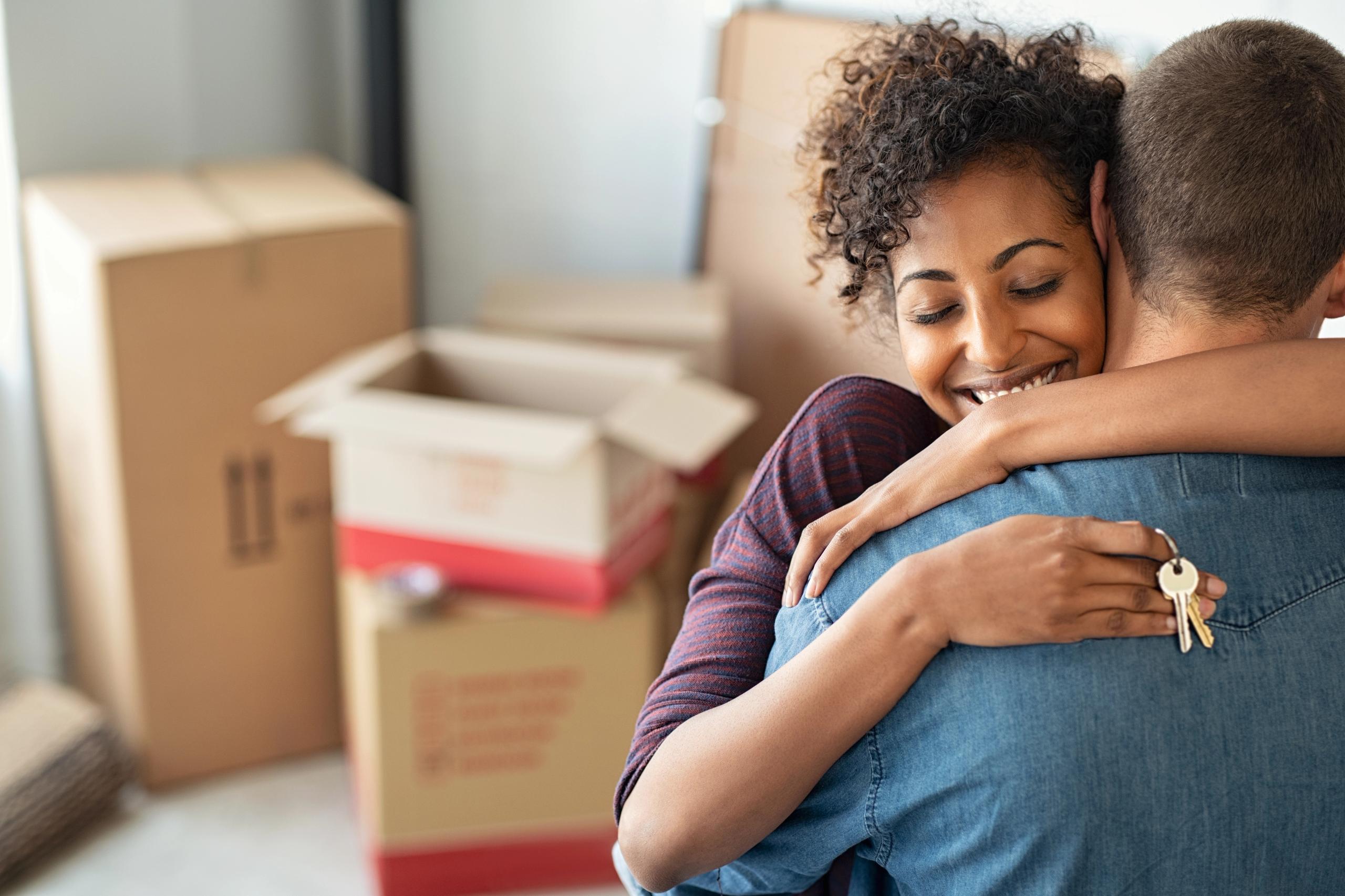 Couple in their new home with moving boxes behind them