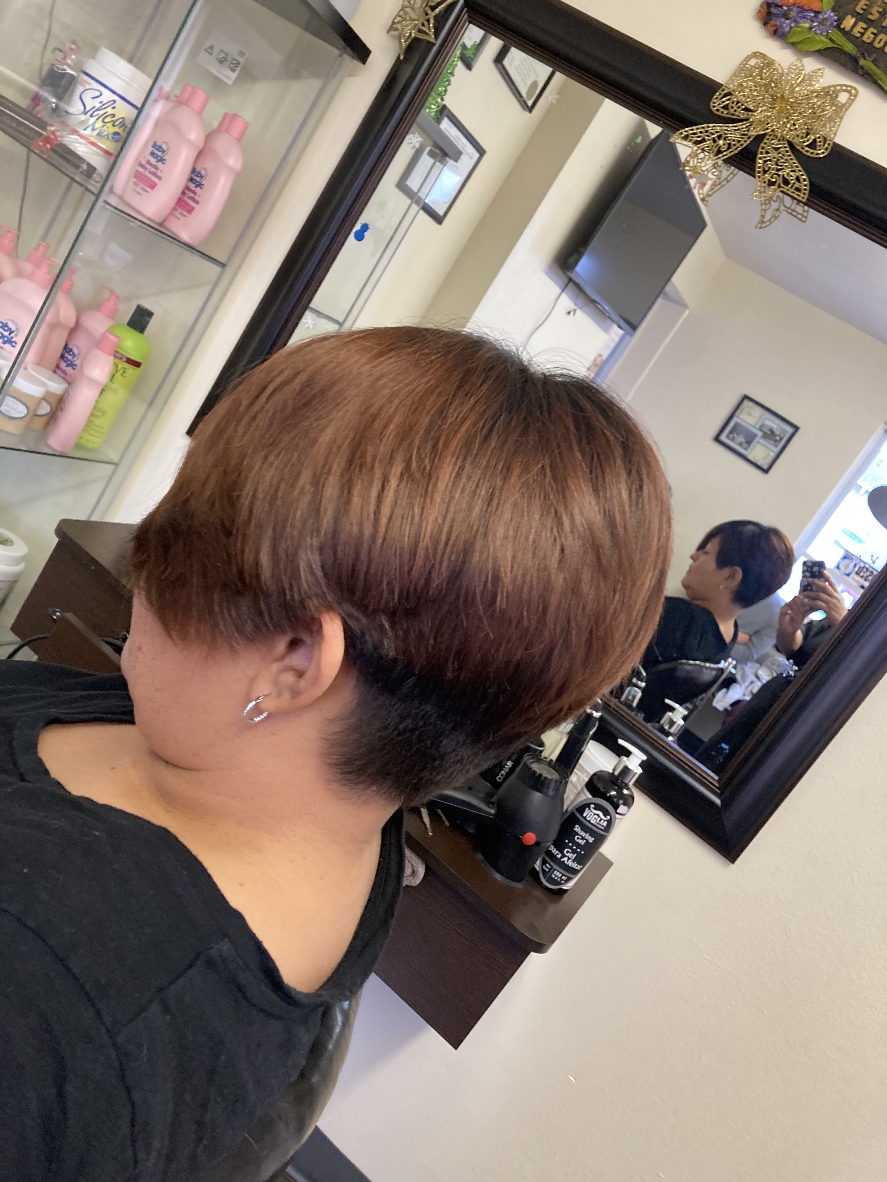 A woman  with a short, bowl-cut hairstyle. The hair is layered, with the top section being longer and the bottom section closely shaved.