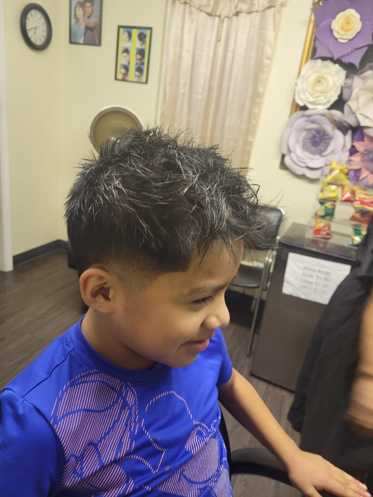 The top hair is left longer and styled in a spiky, tousled fashion for a textured look, while the sides and back feature a smooth, gradual fade that tapers down to the skin near the ears.