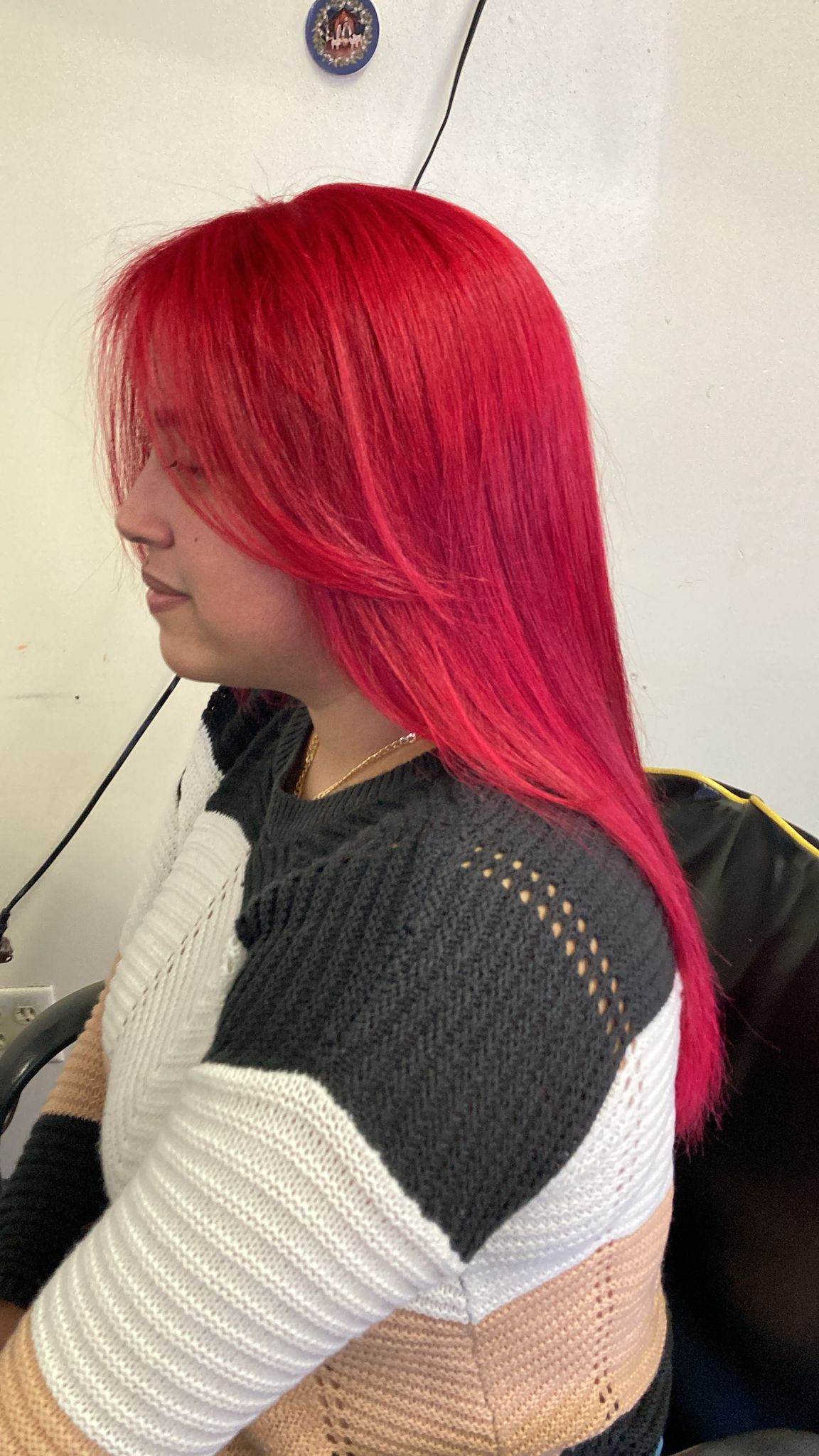 Straight hair, styled in long layers that frame her face. The hair has a smooth texture and flows down past her shoulders. She is seated in a salon chair.